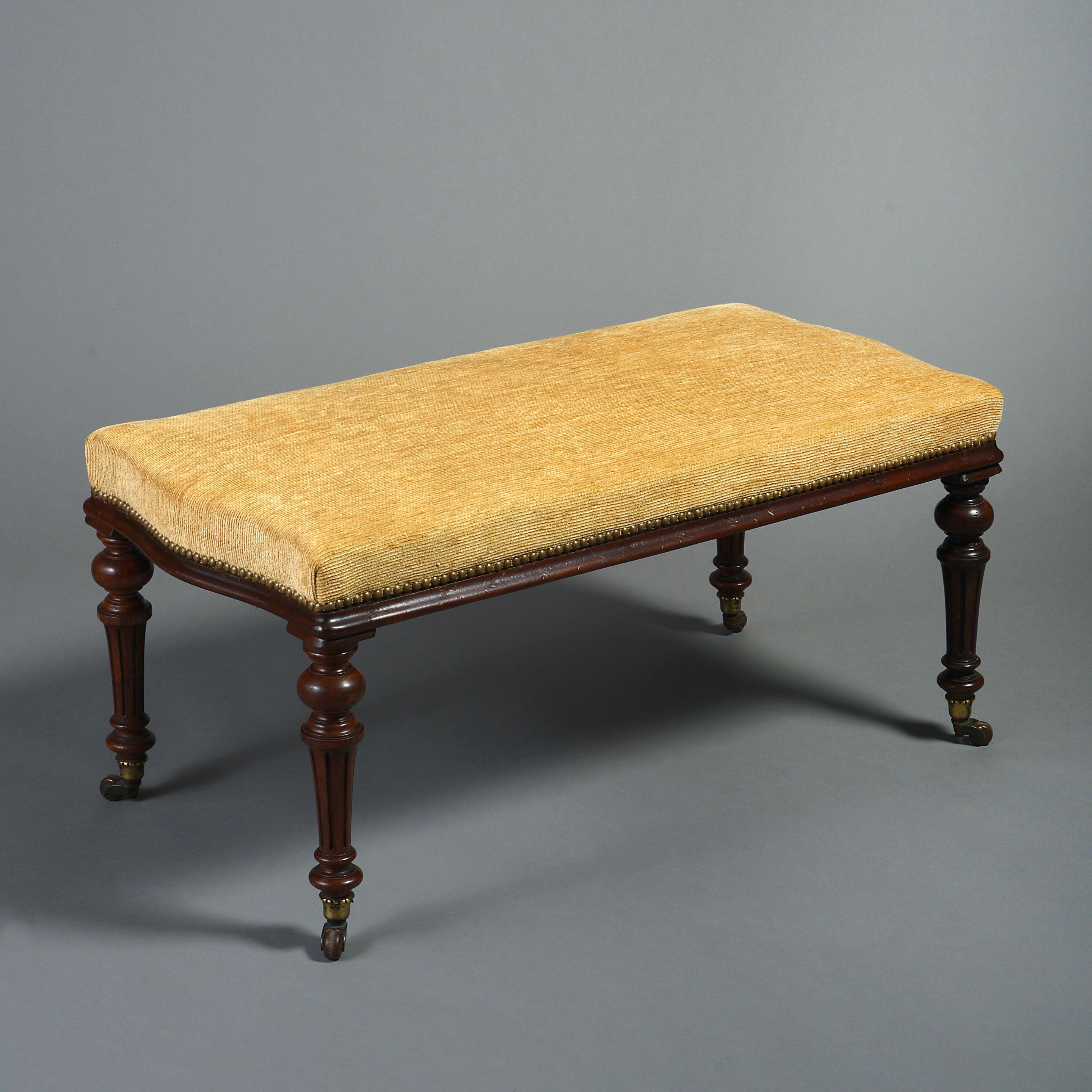 A pair of mid-19th century Victorian Period long stools or benches, each having an upholstered seat with serpentine ends, raised upon four turned burr oak, fluted legs, terminating on the original ceramic castors.