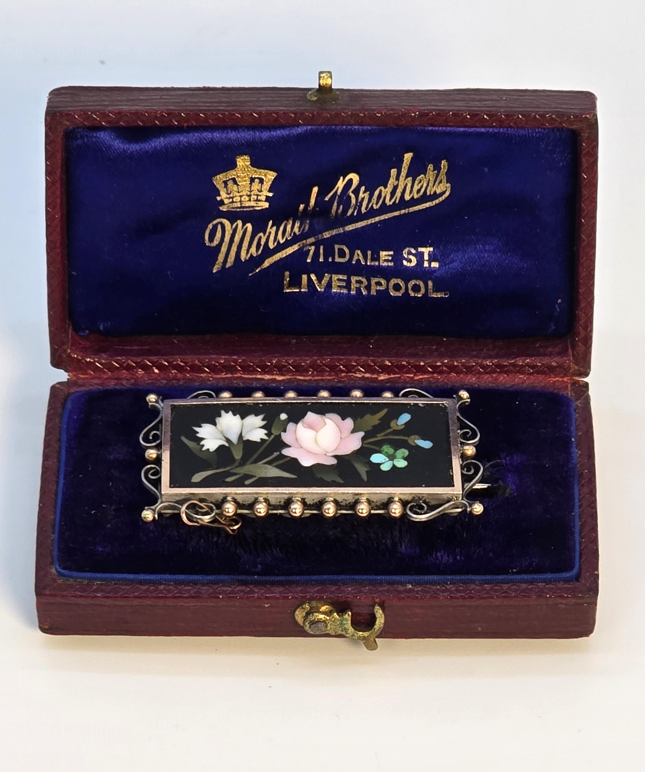 This superb quality mid 19th century Pietra dura brooch is a very fine example decorated with a complicated and detailed display of cut flowers which include turquoise blue forget-me-nots, a pale pink English rose and a white Lilly. All of these