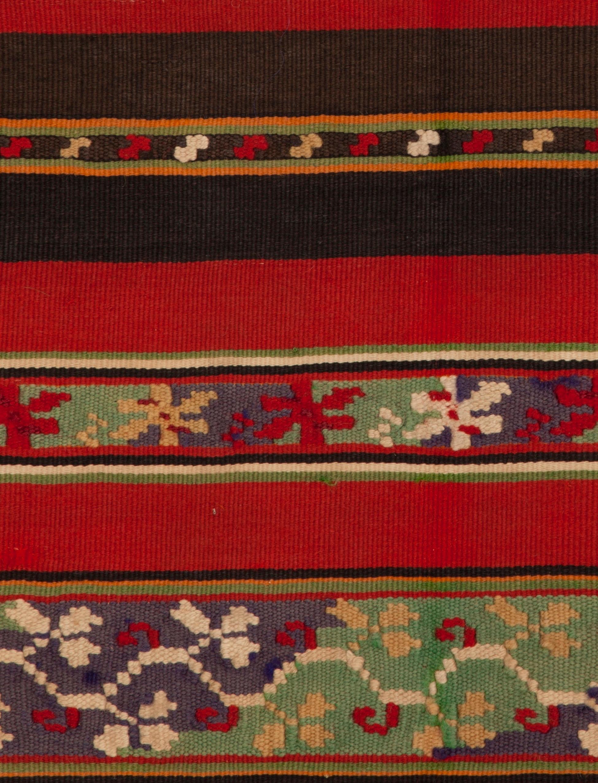 A mid-19th century Romanian finely woven long wool apron with stylized floral motifs and bold red stripes. Bound with 19th century printed cotton. See a similar example in the collection of the Metropolitan Museum of Art (accession # C.I.41.110.22).