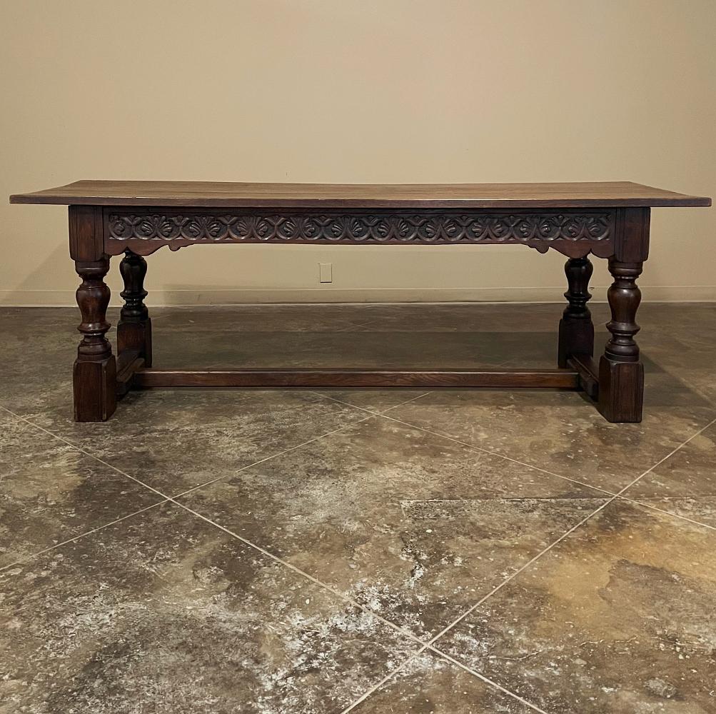 Mid-19th Century Rustic Country French Farm table was hand-hewn from thick, solid planks of old-growth oak, and features massive turned legs on each corner supporting the apron, decorated on one side with stylized foliates carved directly into the