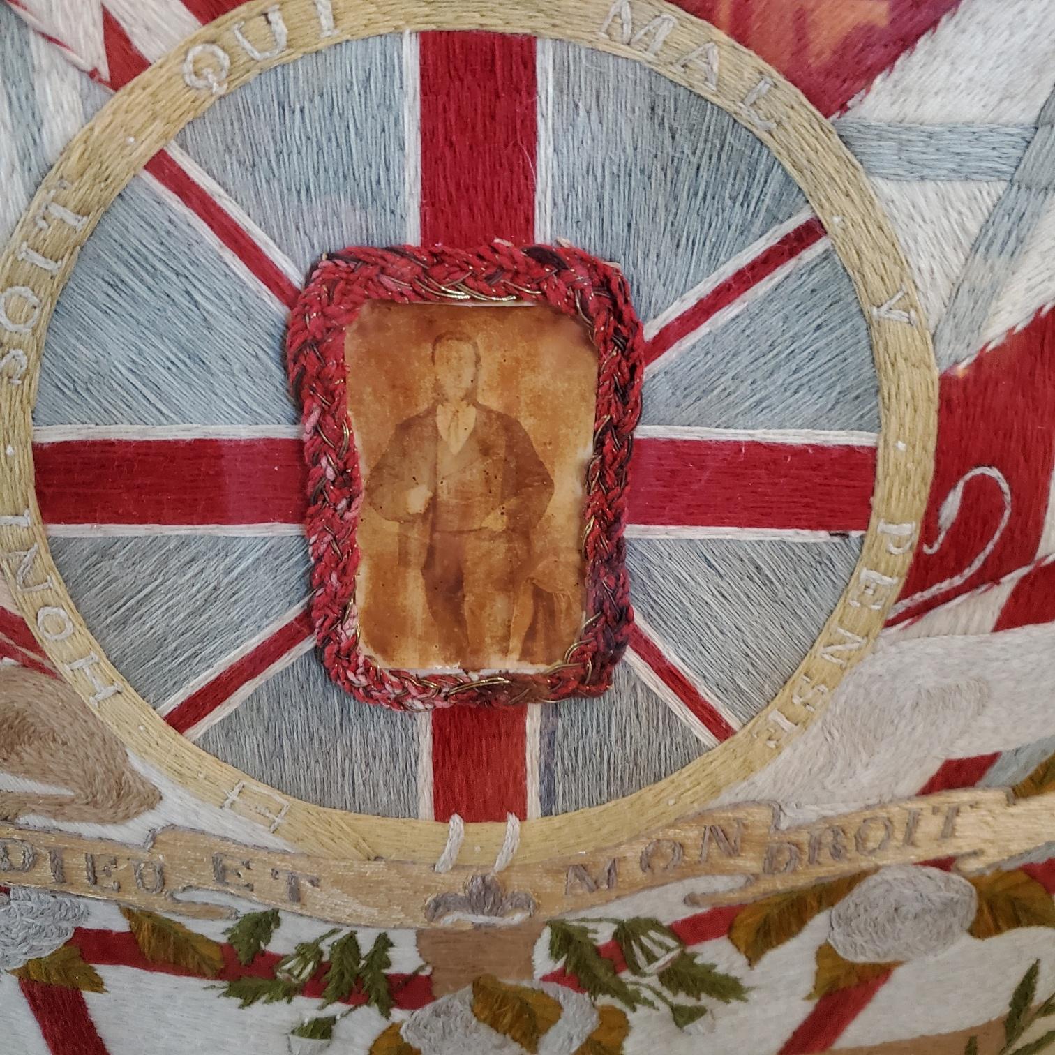 Antique Sailor's elaborate woolwork, circa 1855, with a photograph of the sailor held in a woolwork frame set on the British flag on a cruciform reserve; with the 