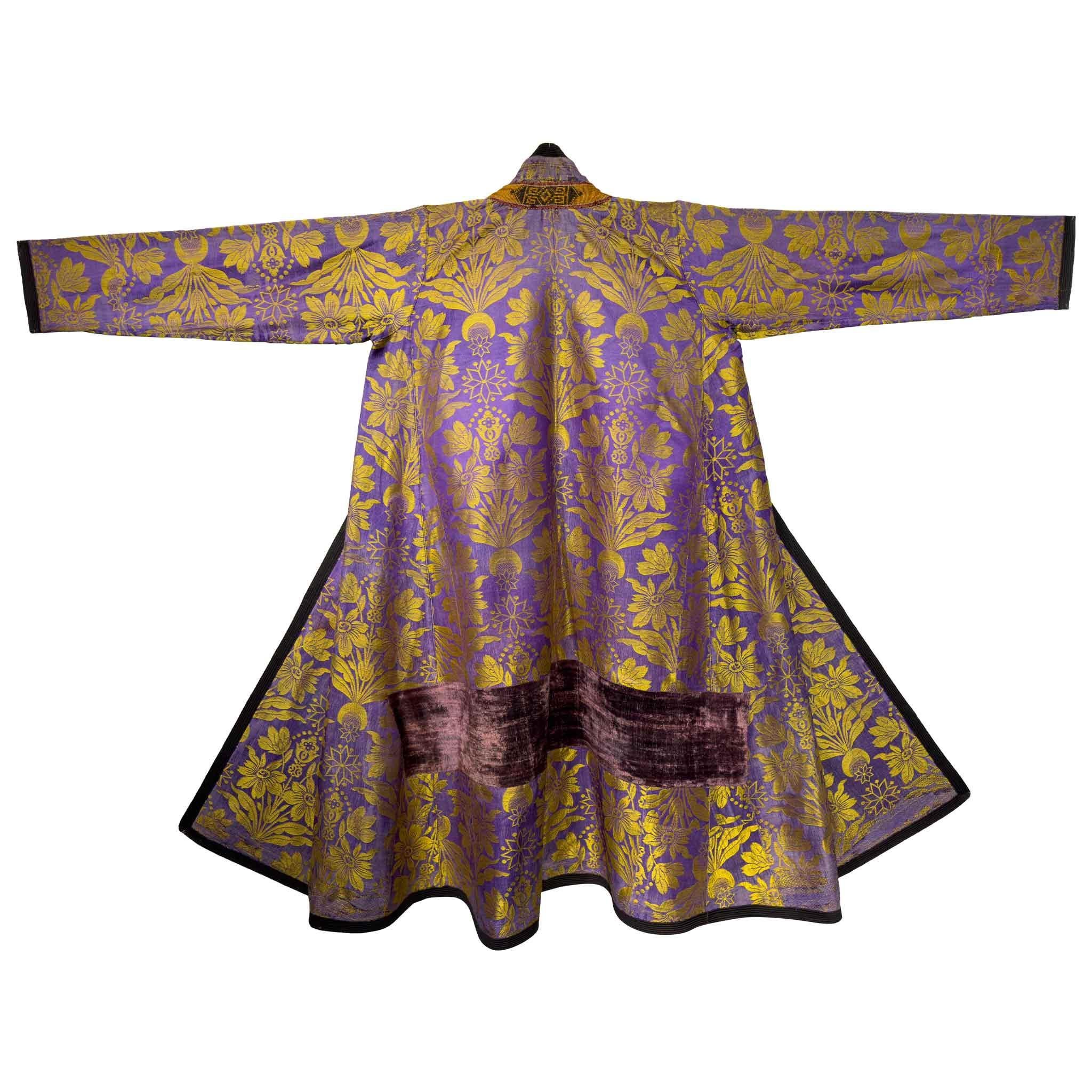 Una straordinaria veste da cerimonia uzbeka della metà del XIX secolo, realizzata in un vivace broccato di seta color lavanda e oro. Il tessuto mostra un elaborato motivo floreale realizzato in seta dai toni metallici, un segno distintivo dei