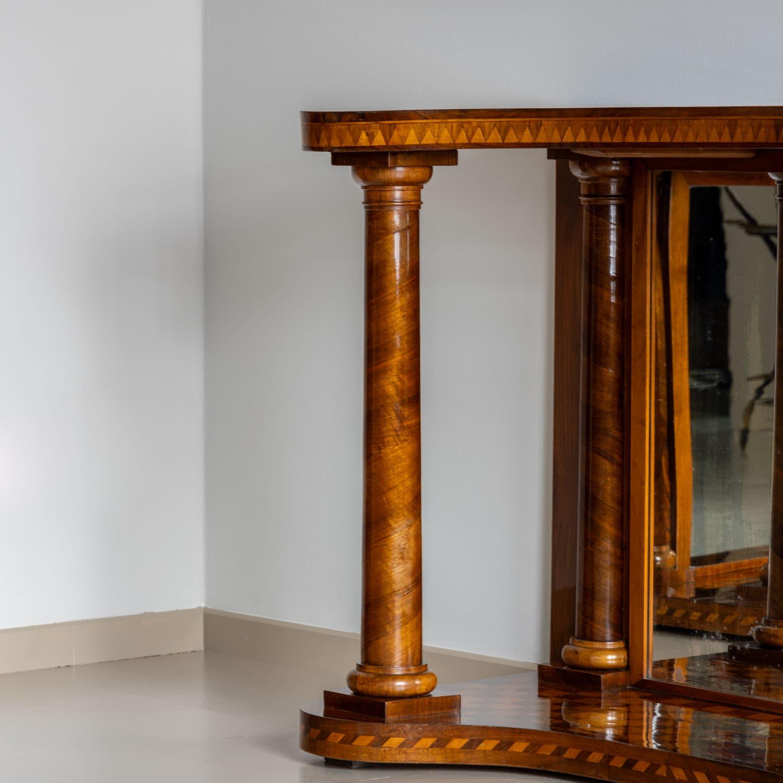 Cette exquise table console du milieu du XIXe siècle présente un panneau arrière en miroir et de robustes colonnes pleines à l'avant, complétées par des demi-colonnes à l'arrière. Les panneaux supérieurs gracieusement incurvés reflètent le design de