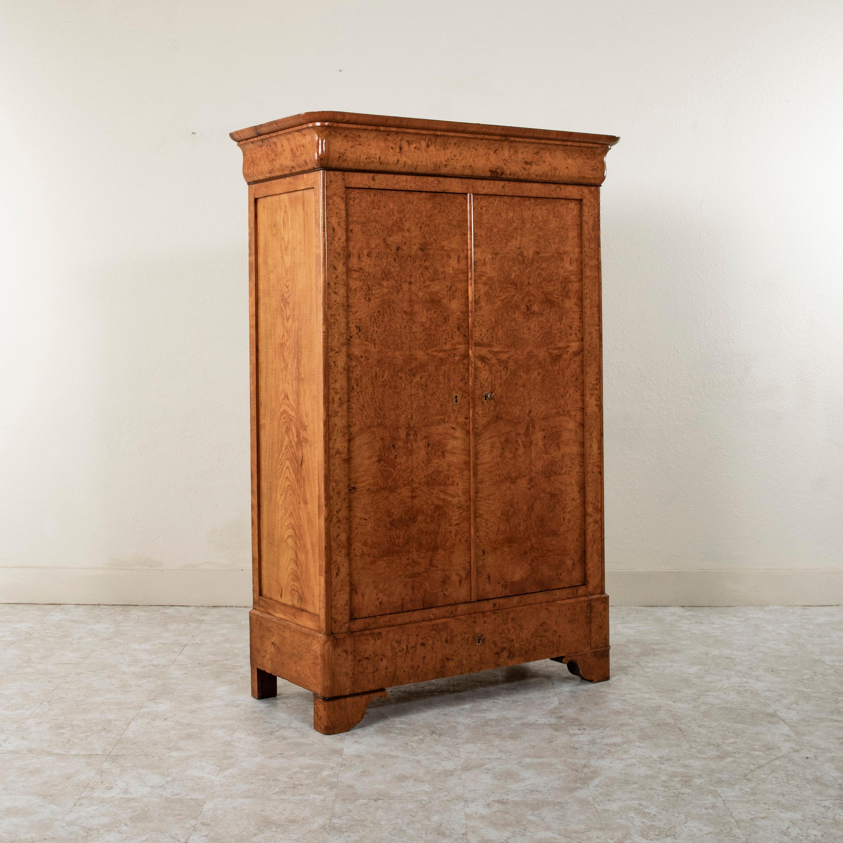 This small scale nineteenth century French armoire, called an armoirette, measures 67 inches high and 44.75 inches wide at the cornice. It features the Classic simple straight lines and warm wood tones of the Louis Philippe period. The cabinet has a