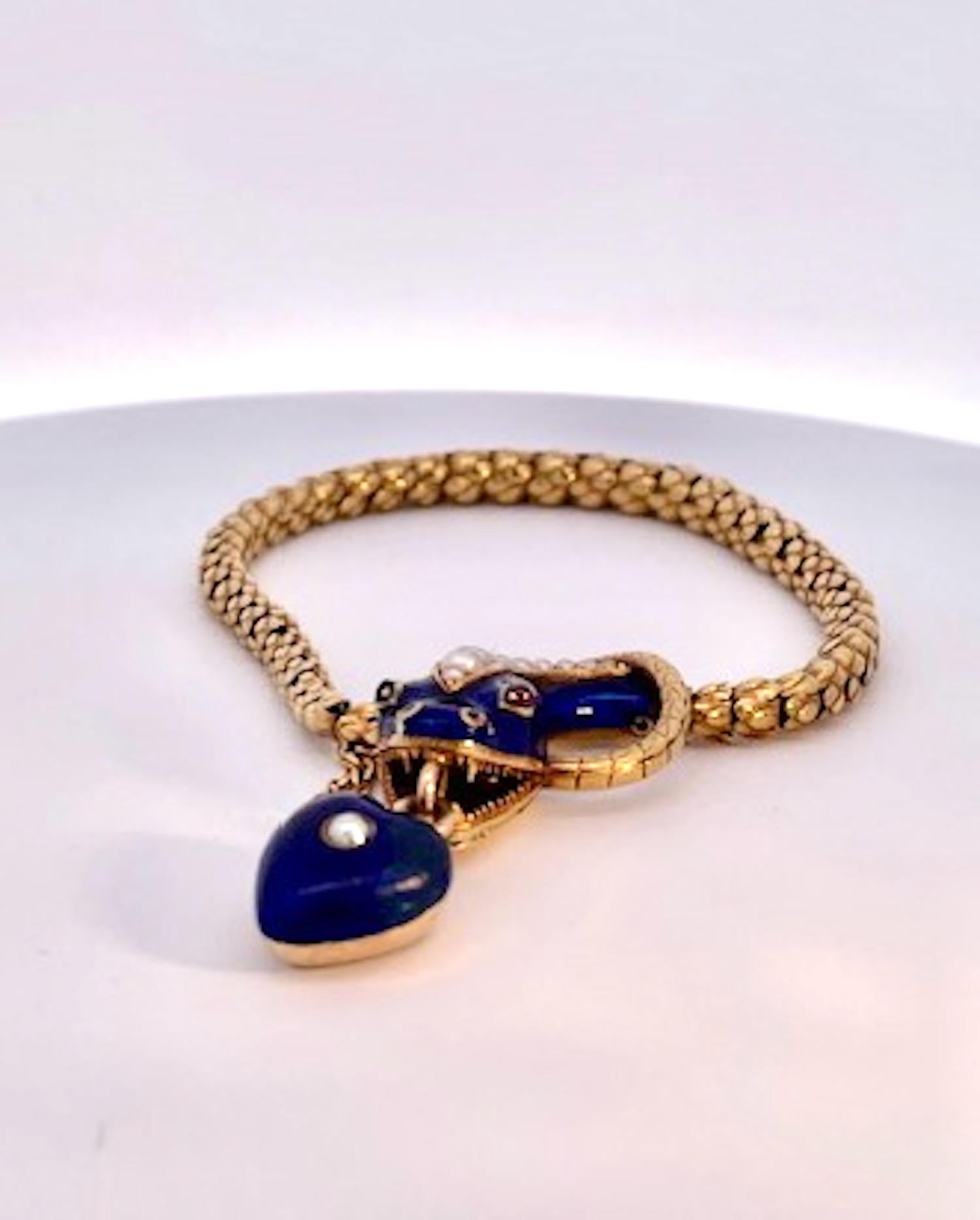 This amazing 14K yellow gold snake bracelet is special.  It is a heavy weight gold chain with a gorgeous snake head decorated with Pearls and Ruby eyes and a heart locket hangs from its mouth.  This is all enameled in a gorgeous cobalt blue, the