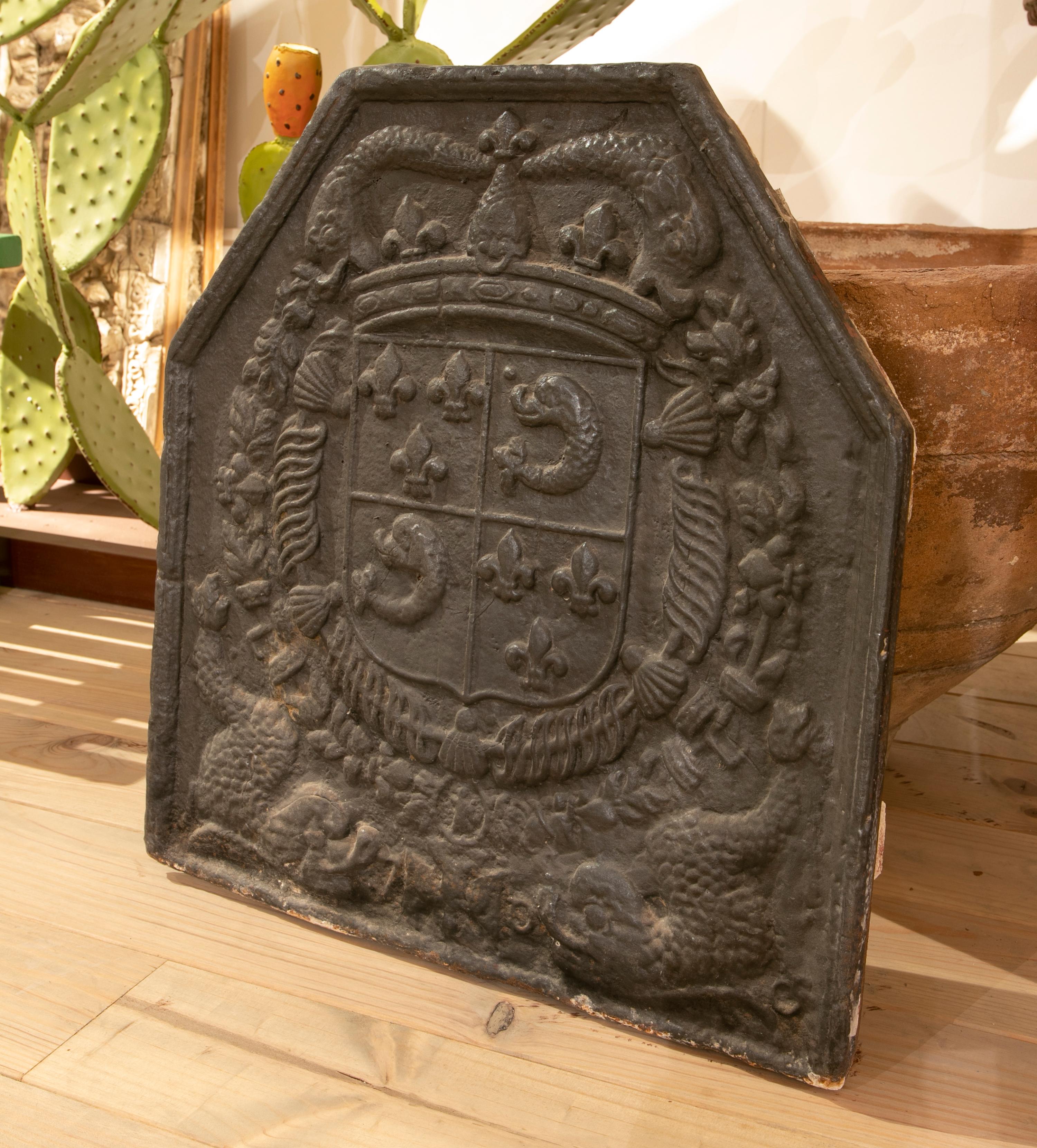 plaque de cheminée en fonte espagnole des années 1850 avec armoiries héraldiques en relief avec emblèmes de la couronne et de la fleur de lys.
 