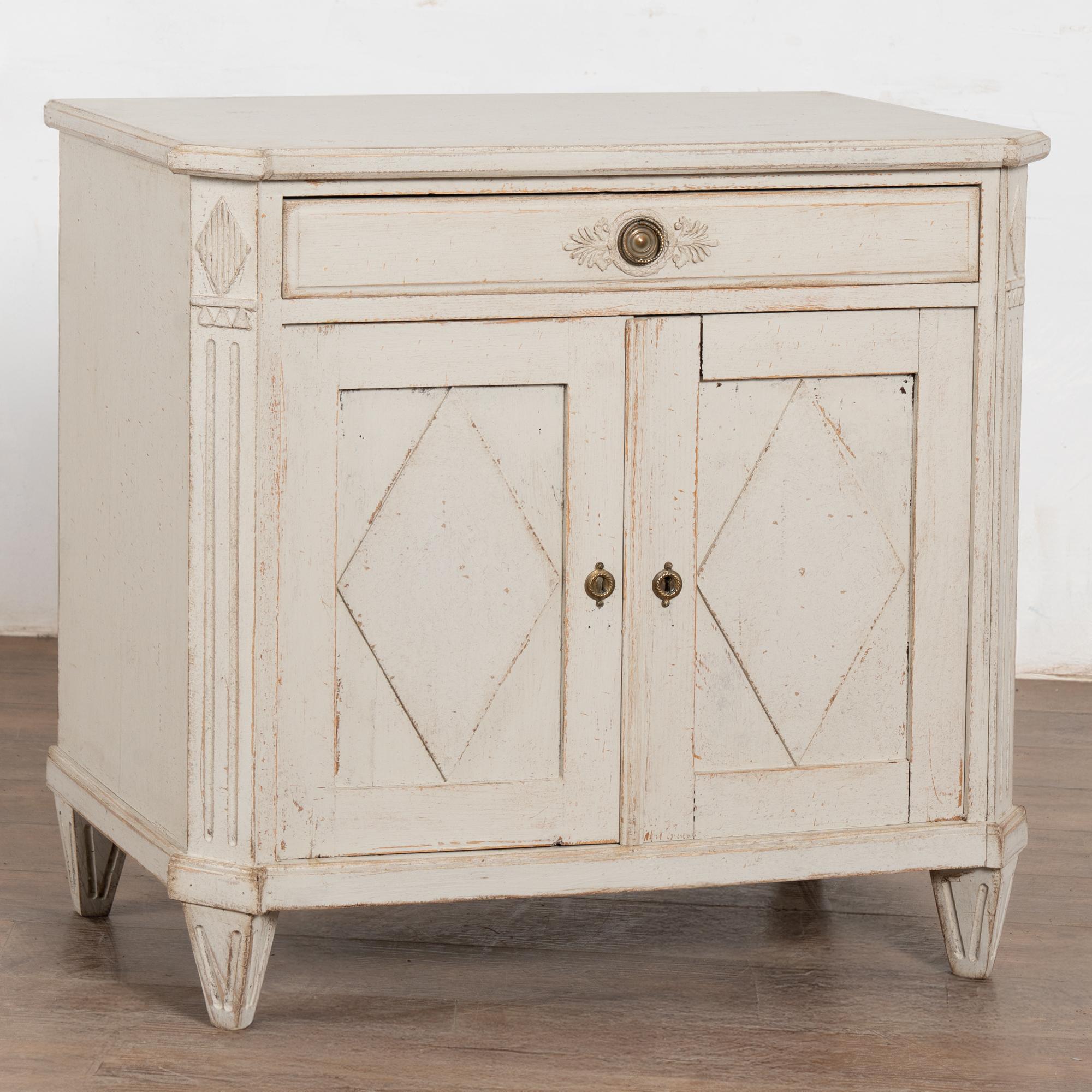 Buffet suédois de style gustavien du milieu du XIXe siècle, fabriqué en chêne et en pin. La nouvelle finition peinte en blanc antique, appliquée par des professionnels, présente des nuances de gris clair et une détresse subtile qui met en valeur la
