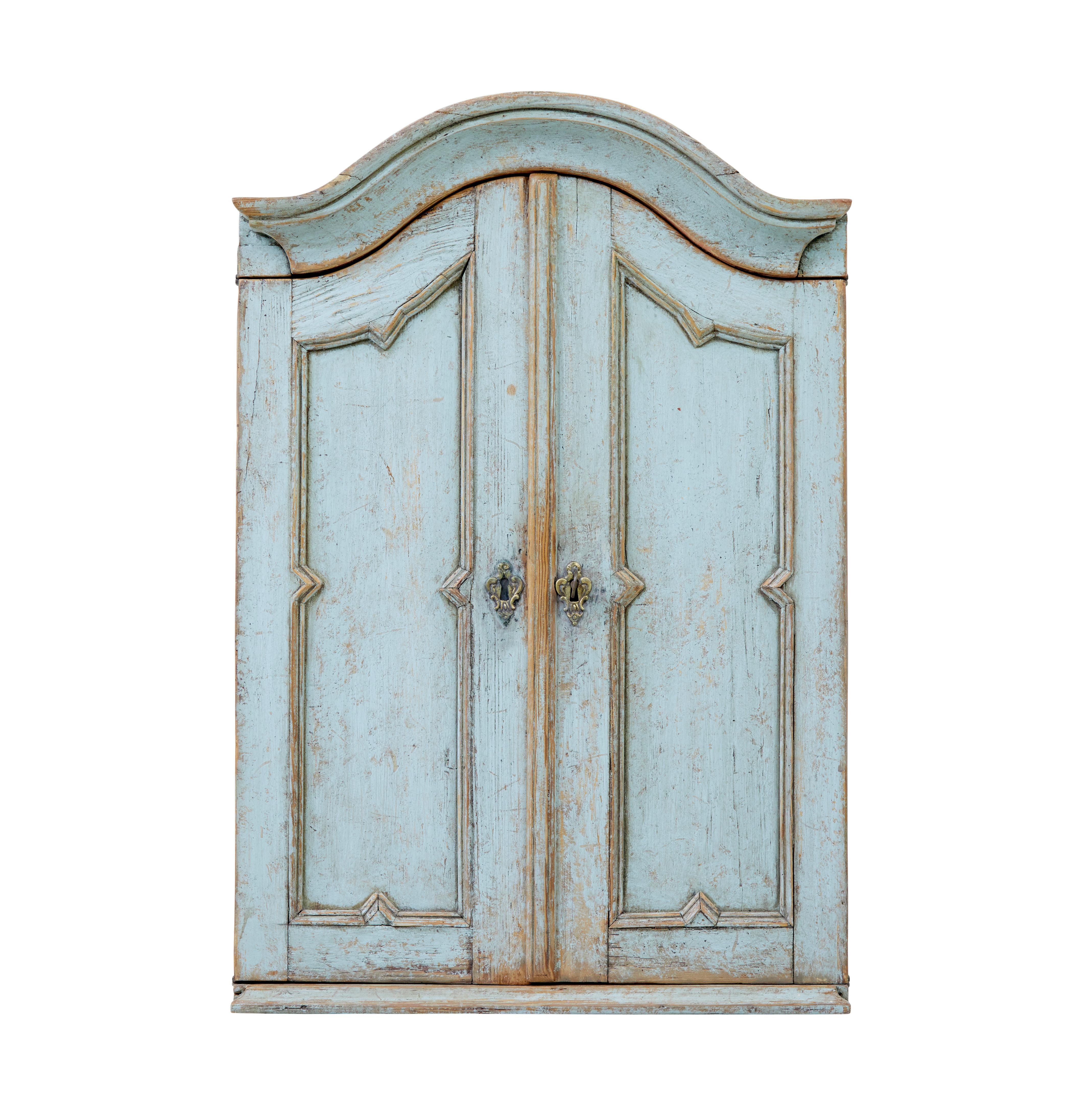 Mid 19th century Swedish painted pine wall cupboard circa 1860.

Elegant piece of Swedish woodwork.  Arch shaped cornice top with decorative mouldings to the double door front.  Original working lock and key opens to reveal an interior of 2 fixed