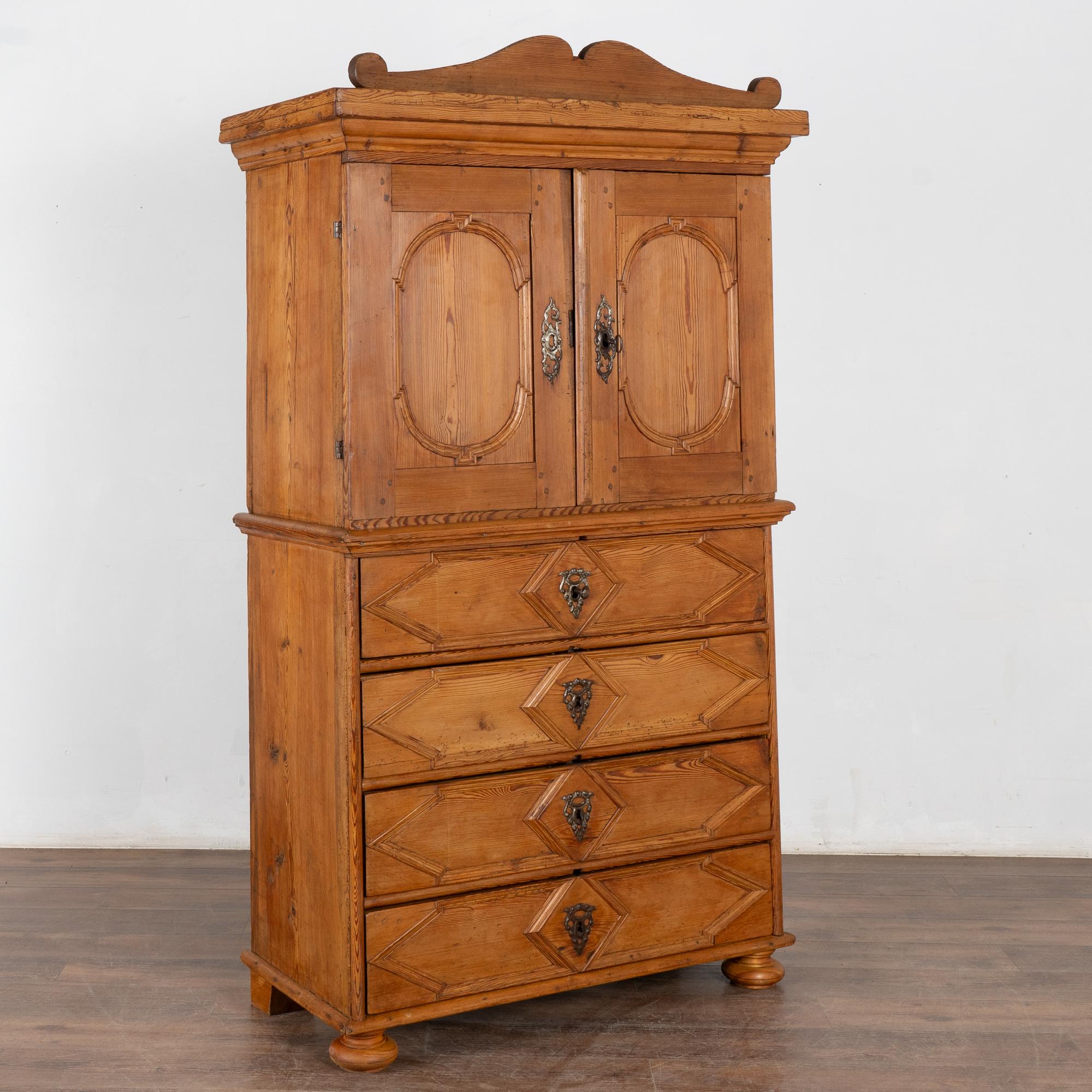 Armadio in pino svedese di ottima fattura, alto poco più di 6' e con piano decorativo (rimovibile).
Due ante su quattro cassetti; l'interno contiene due ripiani standard e un ulteriore ripiano superiore con un tradizionale portacucchiaio.
Le ante