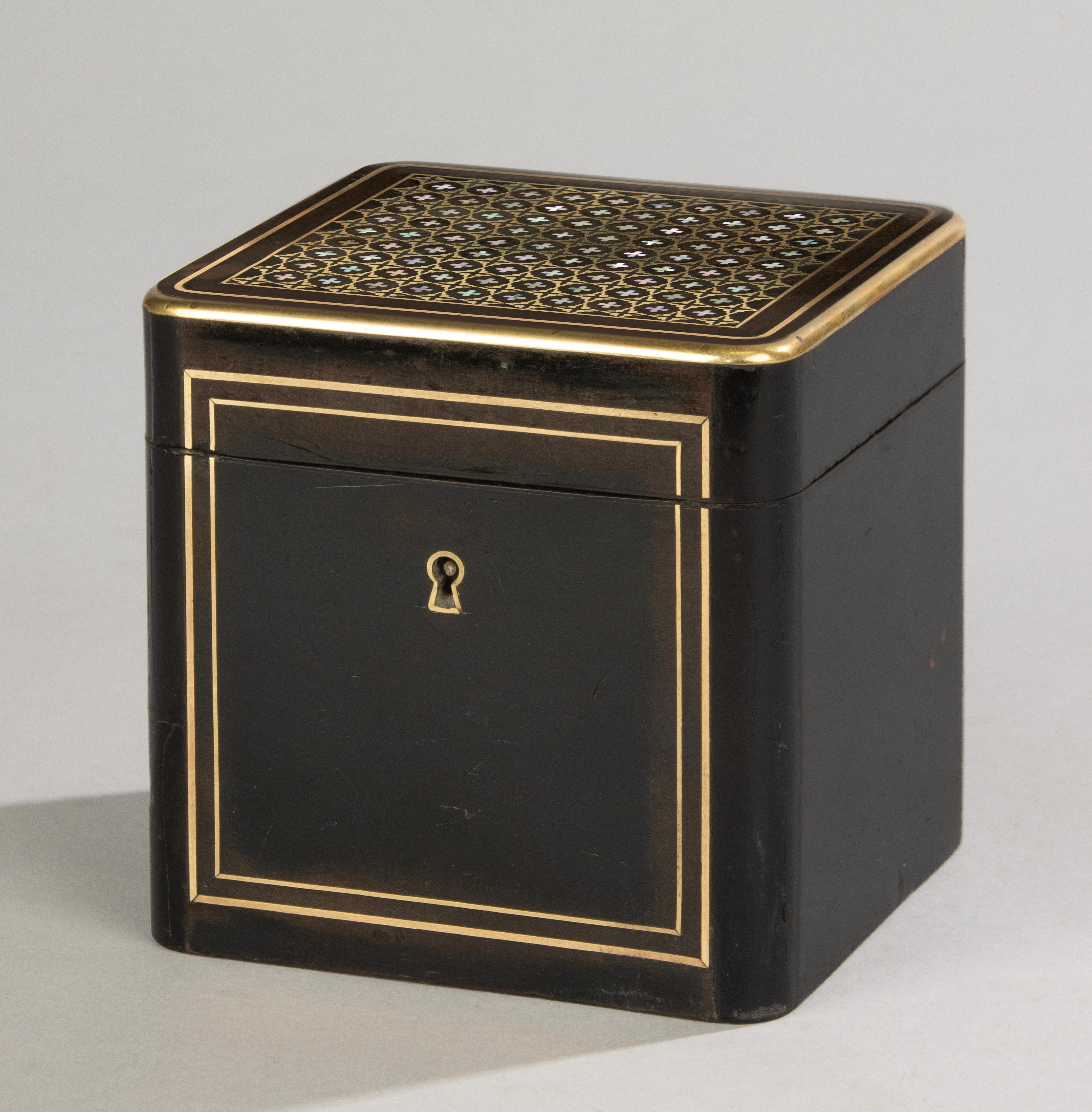 Elégante boîte à thé d'époque Napoléon III, finement décorée d'une incrustation de nacre formant un motif géométrique de trèfle sur le couvercle, encadrée d'une délicate cordelette en laiton. La riche surface laquée noire et les tons chauds du