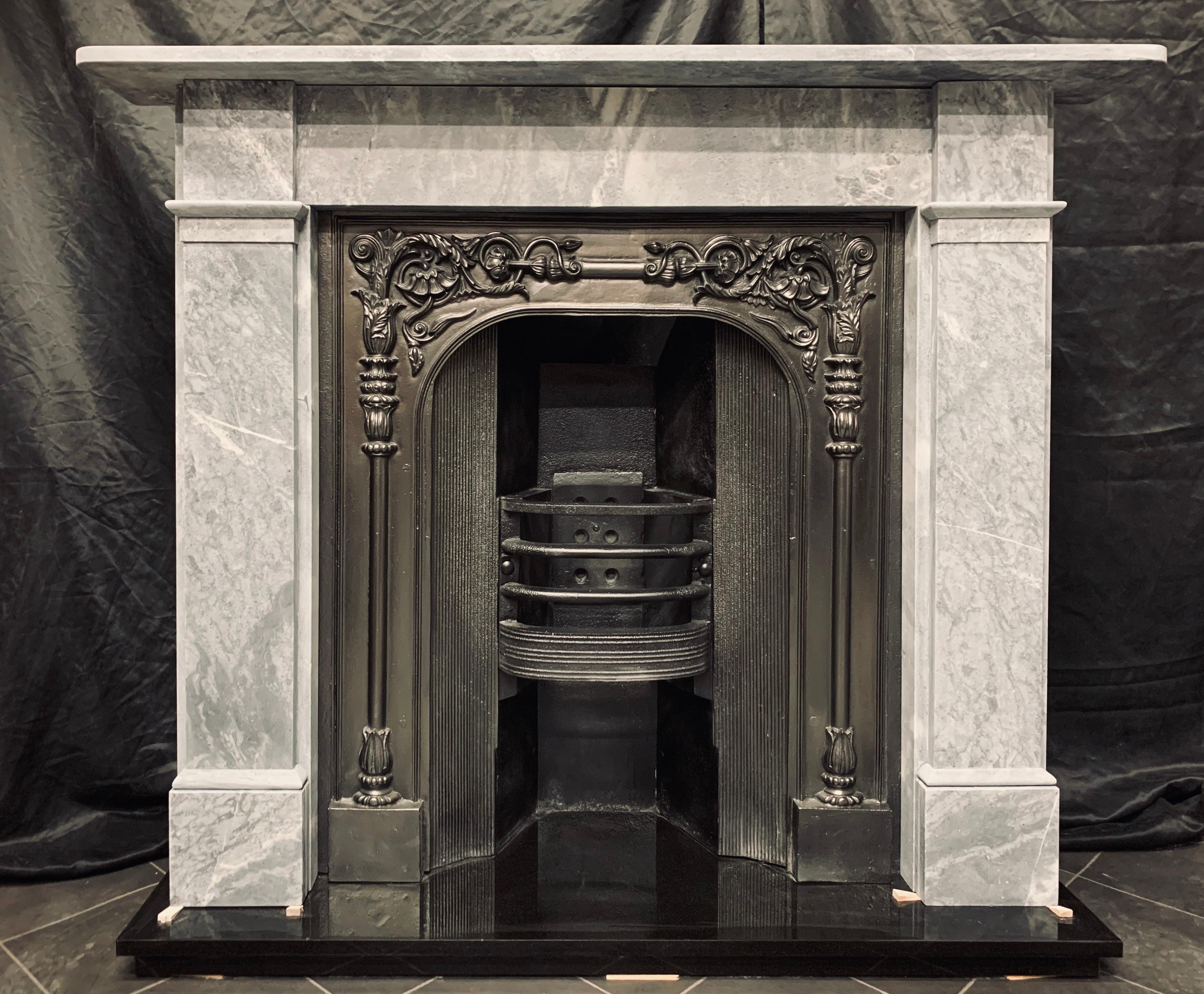 A charming early Victorian 19th century variated dove grey Bardigilo marble fireplace surround, with charcoal accents. A deep, simple shelf sits above an unadorned frieze flanked by stepped jambs with separation splayed capping to the frieze line,