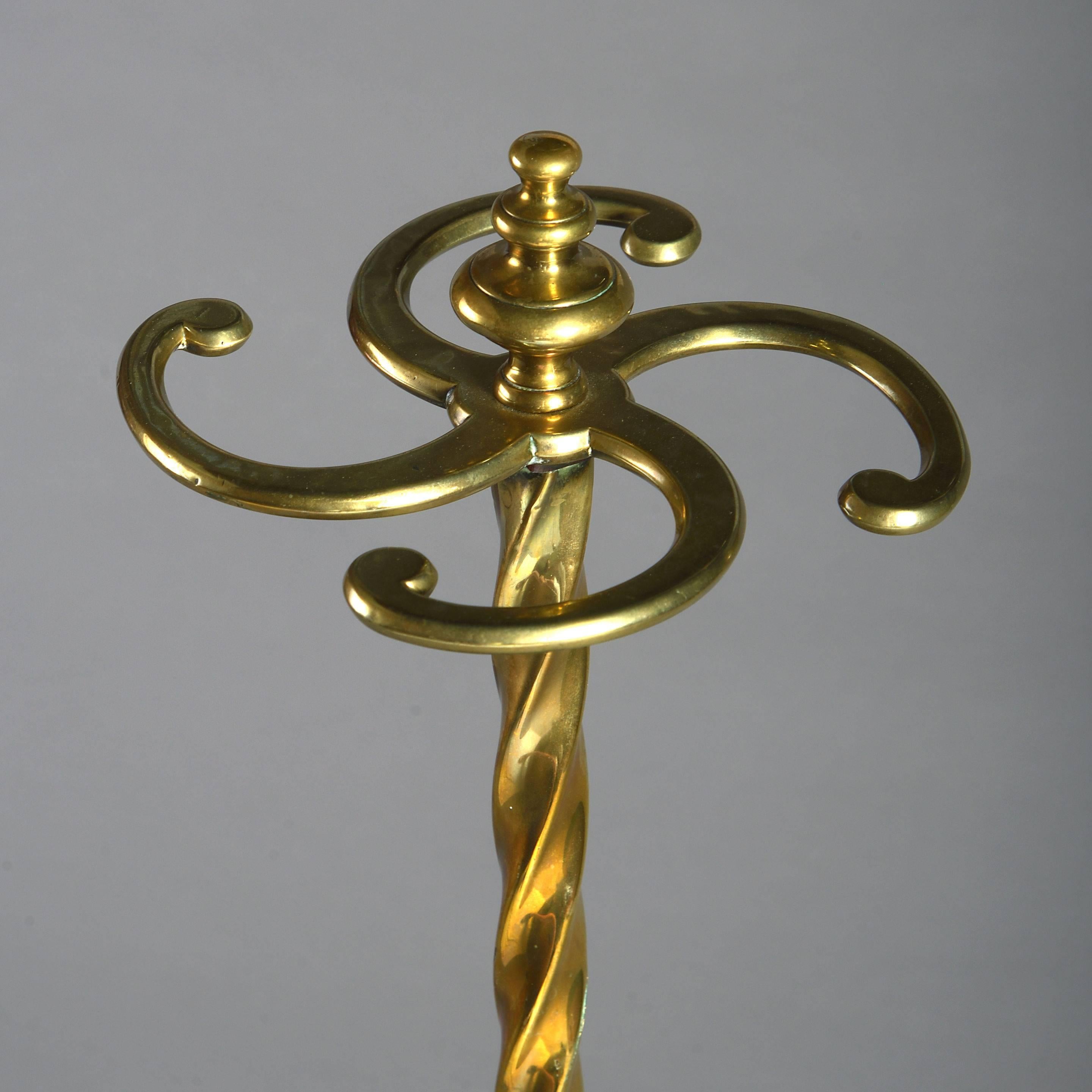 A fine and unusual tall Victorian brass stick stand, the four scrolling divisions with turned finial, surmounting a twisted shaft and set upon a cast iron drip tray, terminating in four brass hairy paw feet.