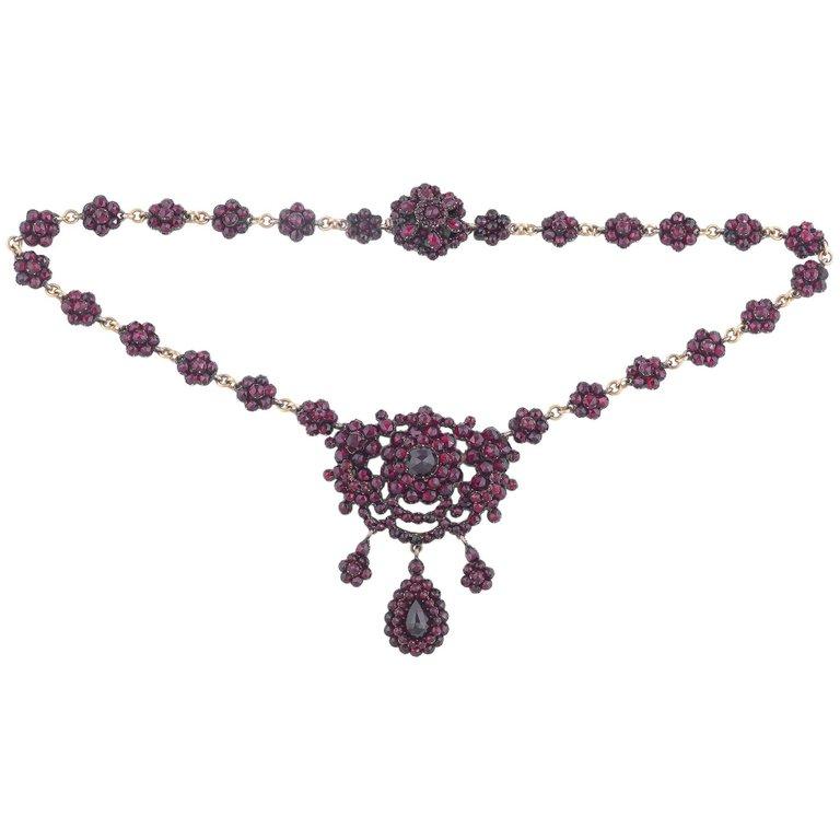 
Victorian bohemian garnet necklace. This piece is set in low carat gold with pretty garnet flowers and smaller drop flowers. Circa 1870-80,

Measures: 42cm long and the central drop measures 6cm