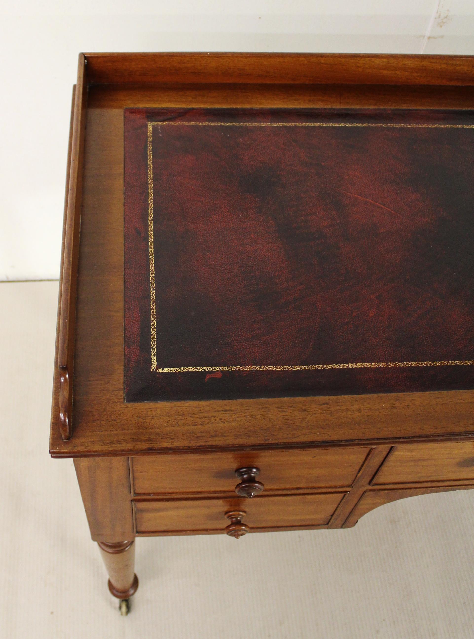 A very good mid-Victorian period mahogany writing table. With a galleried up-stand to the top and fitted with a sumptuous red leather writing surface. There is an arrangement of one long central drawer flanked by a pair of shorter end drawers.