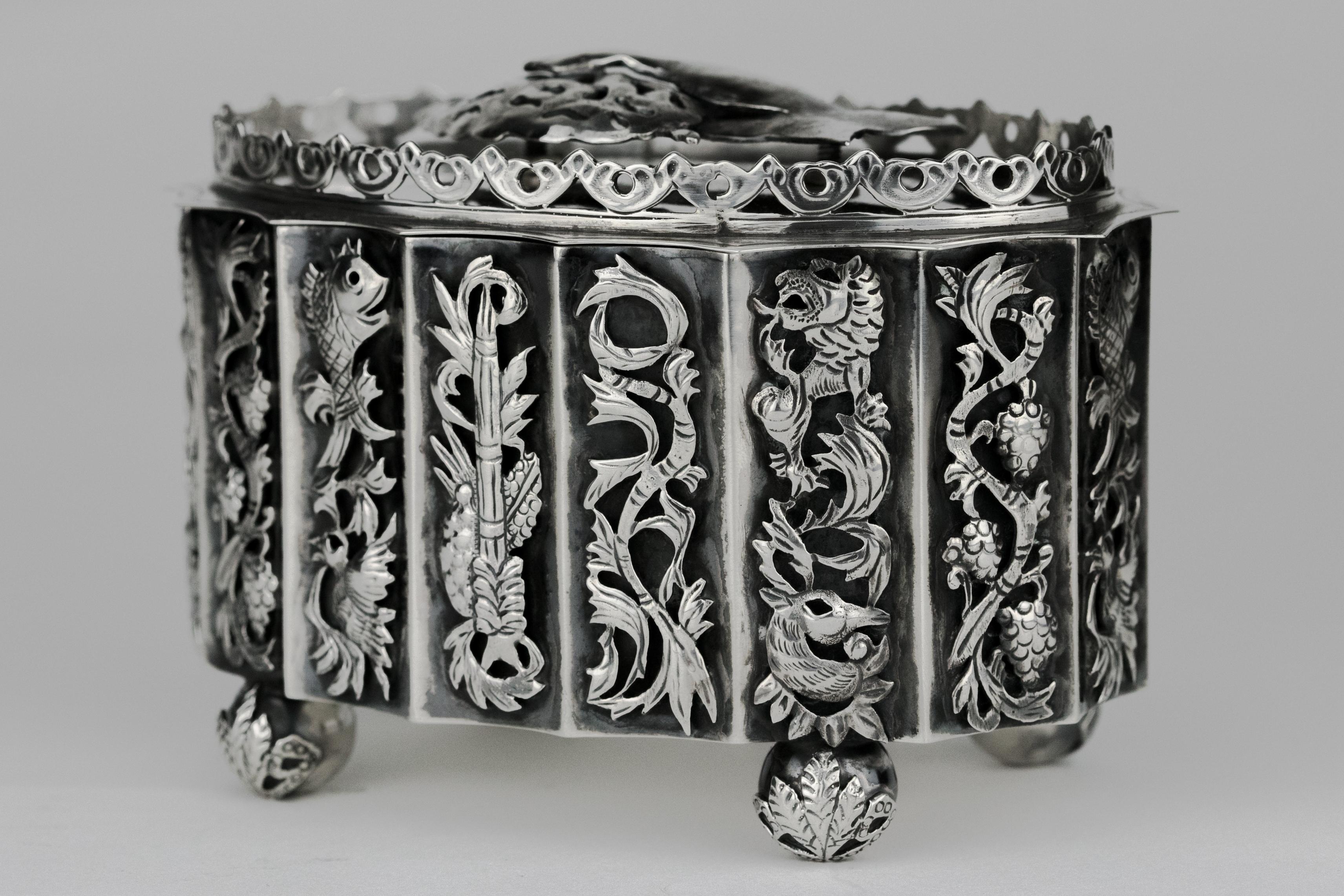 Handmade sterling silver Etrog container by Peter Ehrenthal, New York, USA, circa 1960.
The cover is decorated with a hand holding an Etrog with hand-hammered and cut-out technique.
Handcut lattice work is applied to the container with five