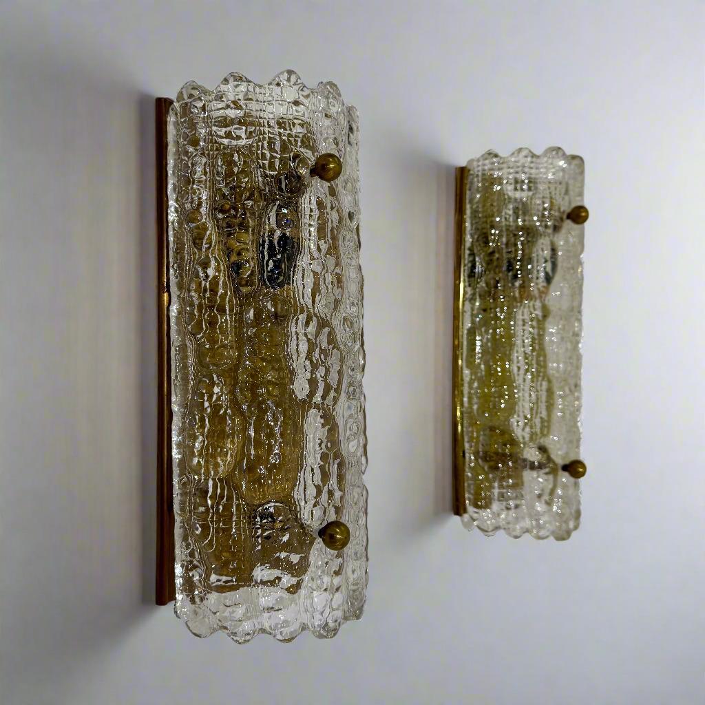 Coppia di appliques in vetro artistico di Carl Fagerlund per Orrefors. Svezia, anni '60 circa. Semitrasparenti in vetro a cupola con texture pesante, montate su piastre posteriori in ottone invecchiato. Elettrificato per il mercato statunitense.