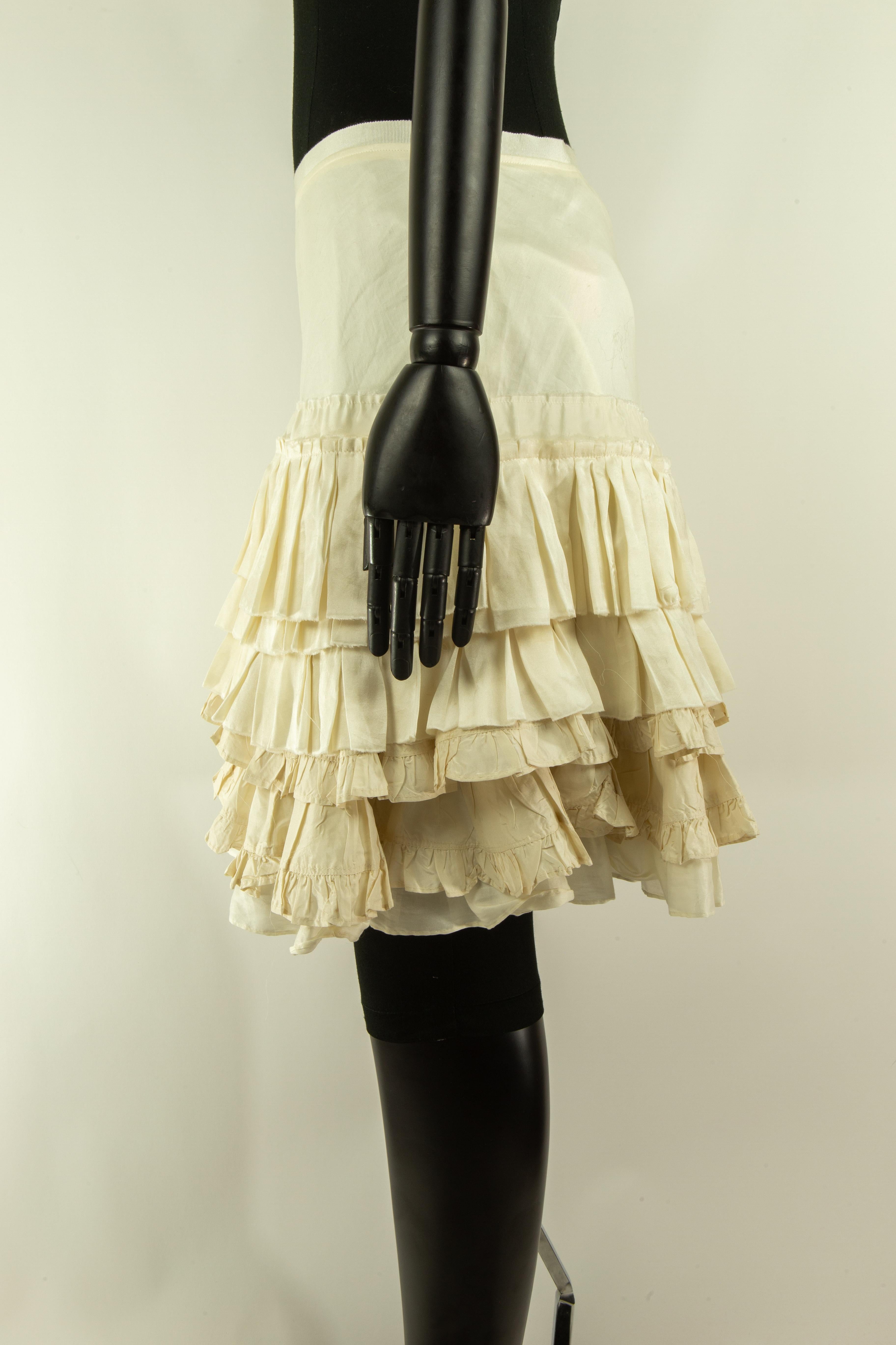 A Chloé pearl white skirt from the mid-2000s adorned in tiered ruffles from the hip down. The skirt is mid-thigh length fastened with a zip along the centre back. 
