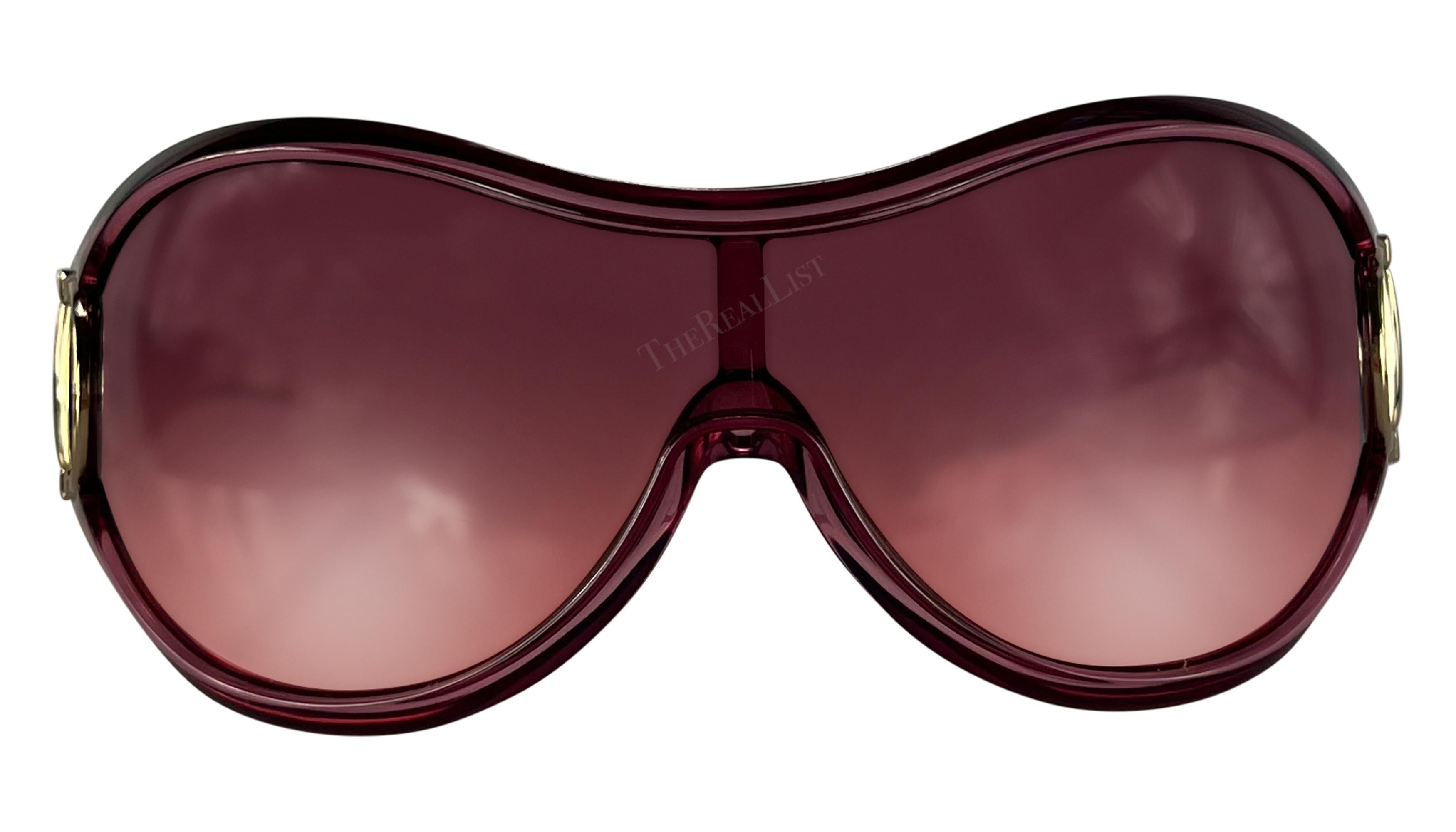 Ich präsentiere eine fabelhafte hellrosa Gucci Sonnenbrille mit Schild. Diese übergroße Shield-Sonnenbrille aus der Mitte der 2000er Jahre hat einen transparenten, hellrosa Rahmen, rosafarbene Gläser und ist mit silberfarbenen Pferdegebiss-Akzenten