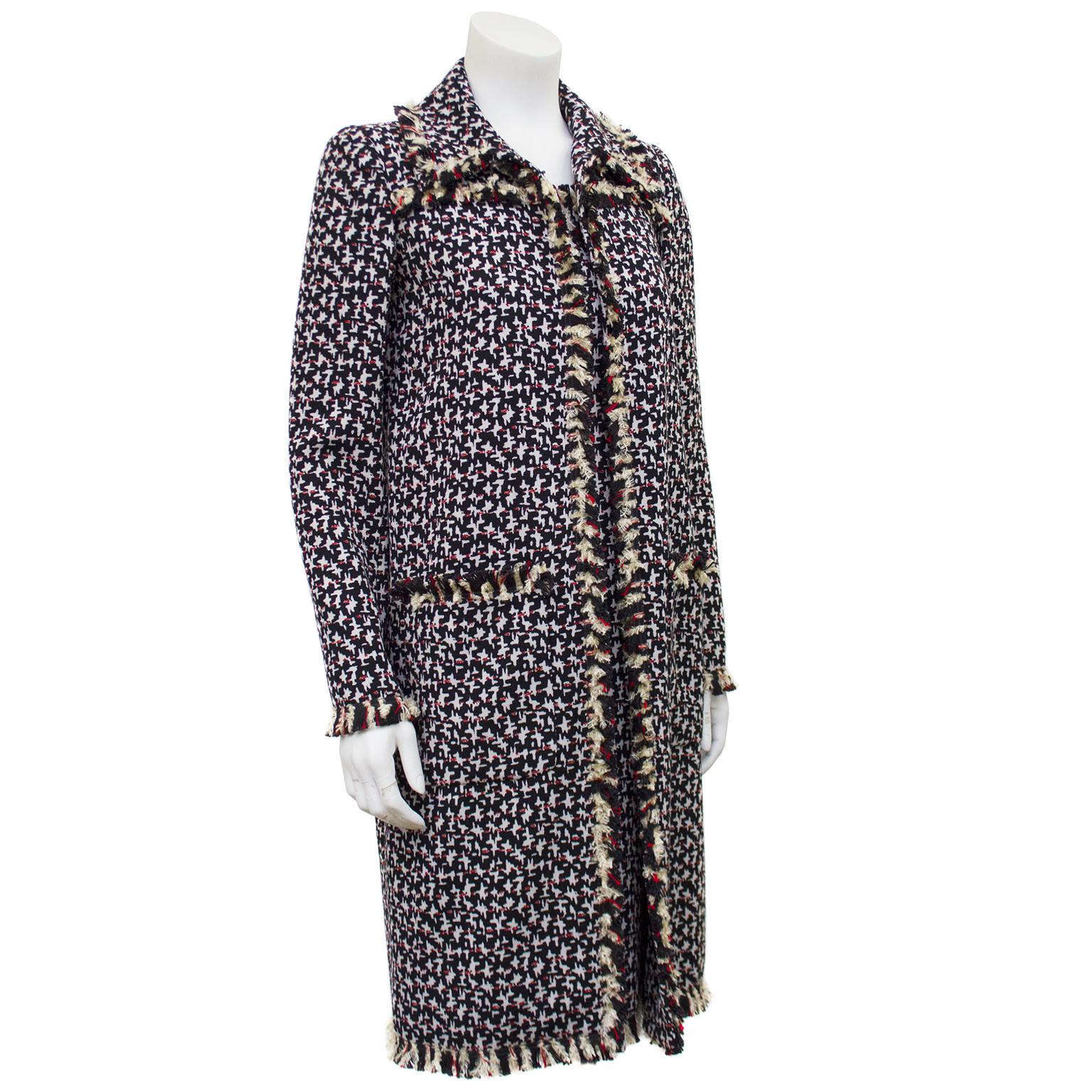 Gorgeous Oscar de la Renta navy and red abstract houndstooth printed dress and coat from the mid 2000s. The long coat is trimmed in matching fringe along the lapel, pockets, cuffs and down the front. Single hook closure at the bust. The sheath style