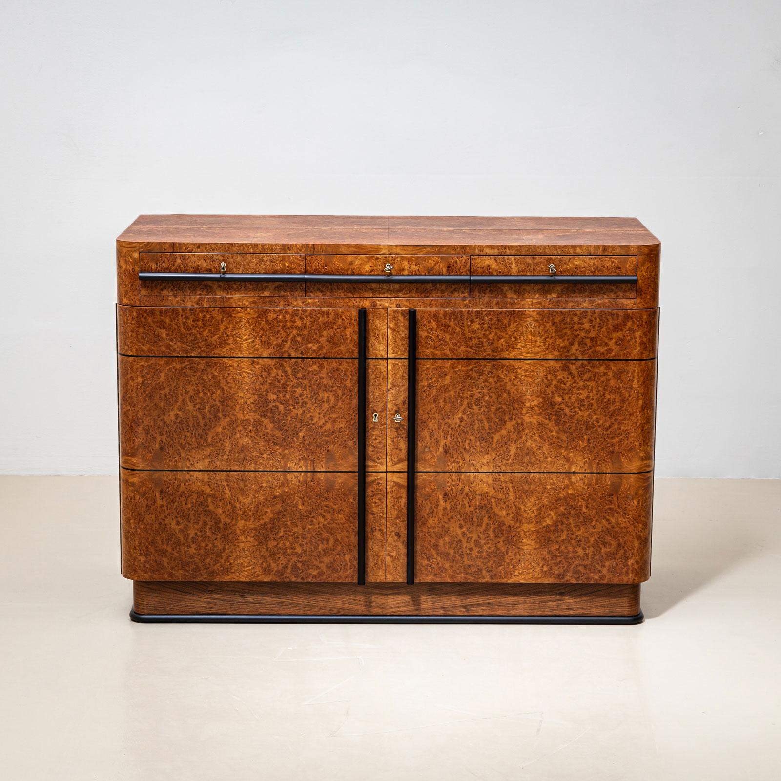 

Élégant buffet Art déco à deux portes, datant de l'Italie des années 1930, dont le placage de racines de thuya confère à l'ensemble un aspect chaleureux et luxueux. La façade comprend trois tiroirs plus petits, accentués par des poignées élégantes