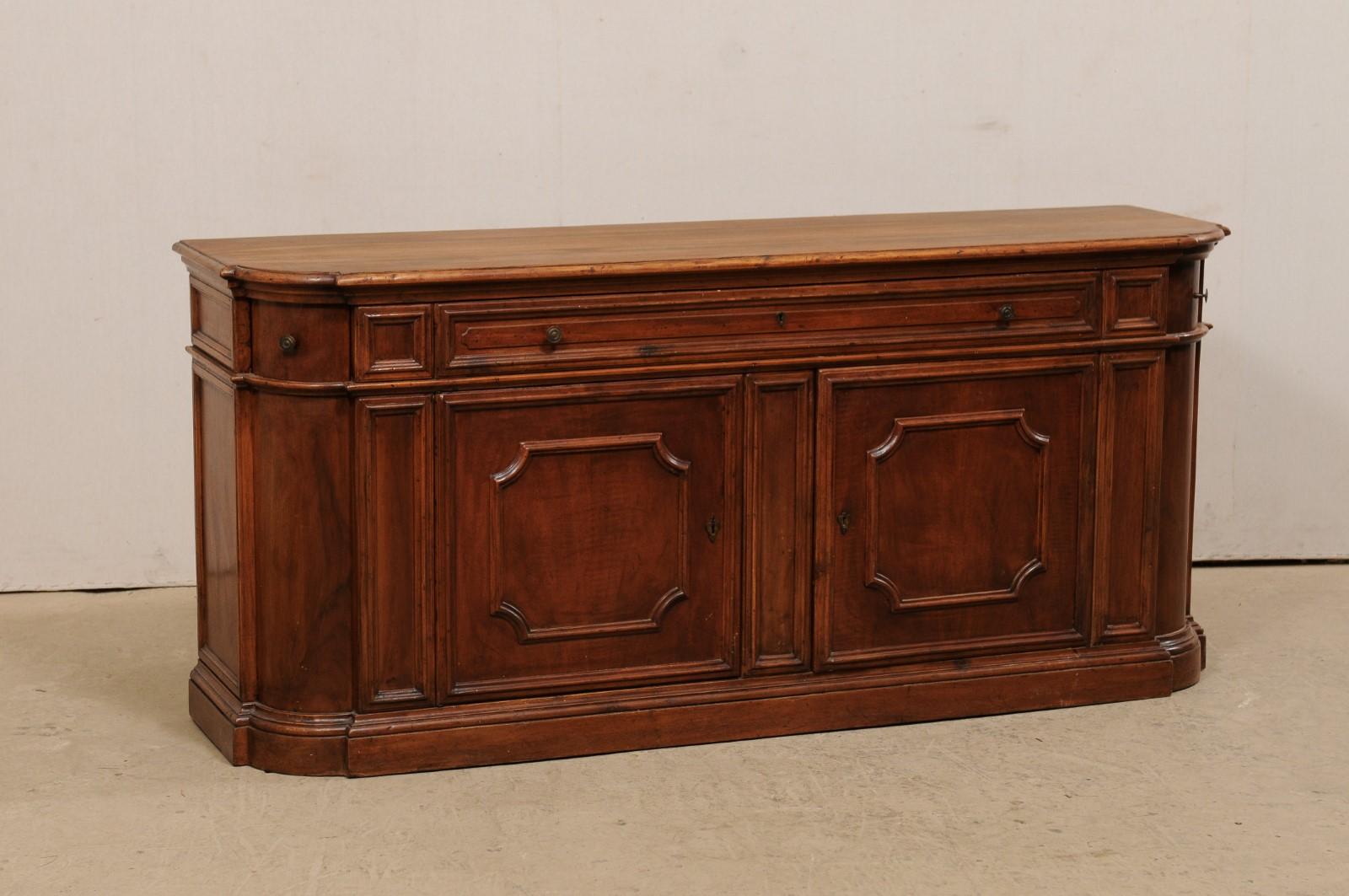 An American wooden buffet cabinet from the mid-20th century. This vintage console cabinet is just over 6 feet in length and has been fashioned from fruitwood with a warm cherry stain. It is accentuated about it's body with nicely molded trim and