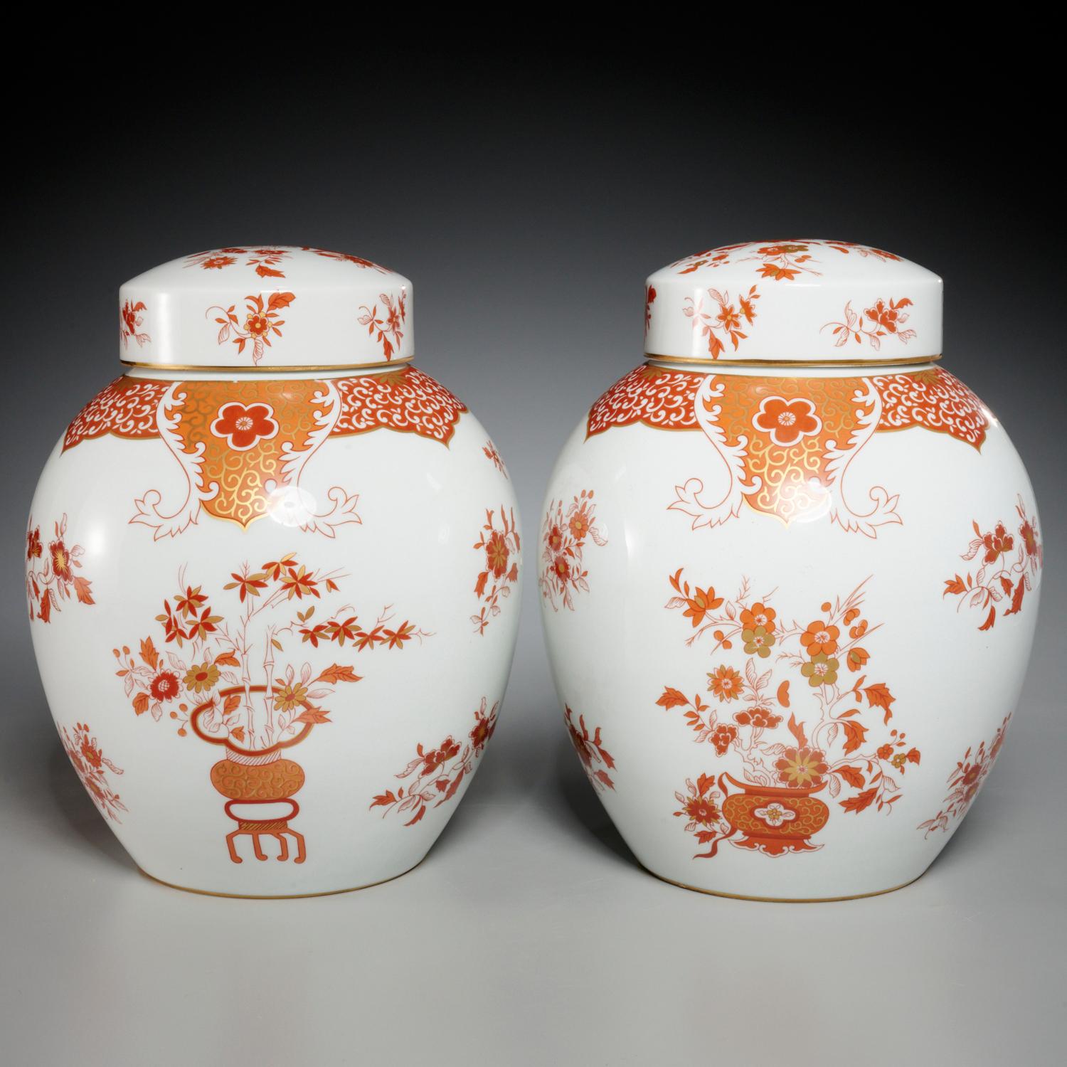 20th c., a pair of Japanese Kutani style porcelain lidded jars, stamped on Porcelaine de Paris underside of foot. The mark indicates the piece was produced in the 1970's. The jars are decorated in deep orange, tangerine and gold motifs on a white