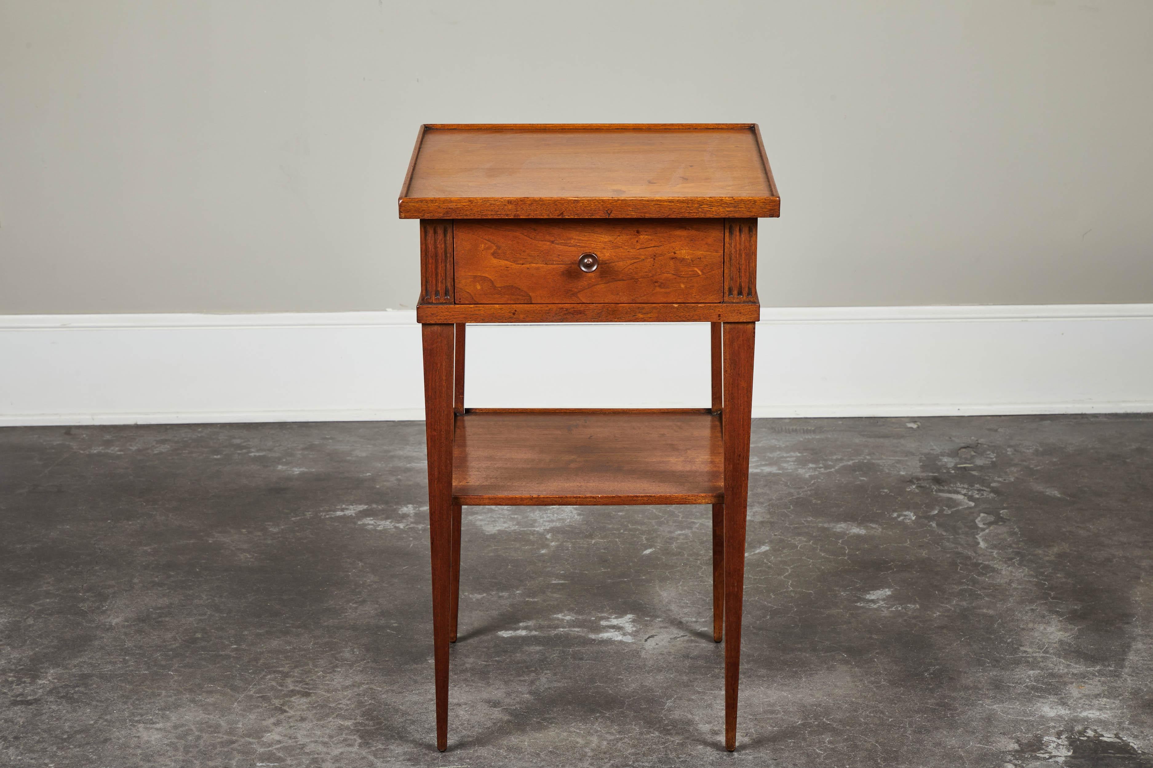 A mid-20th century French walnut Empire inspired side table, with a single-drawer lined with vintage wallpaper.