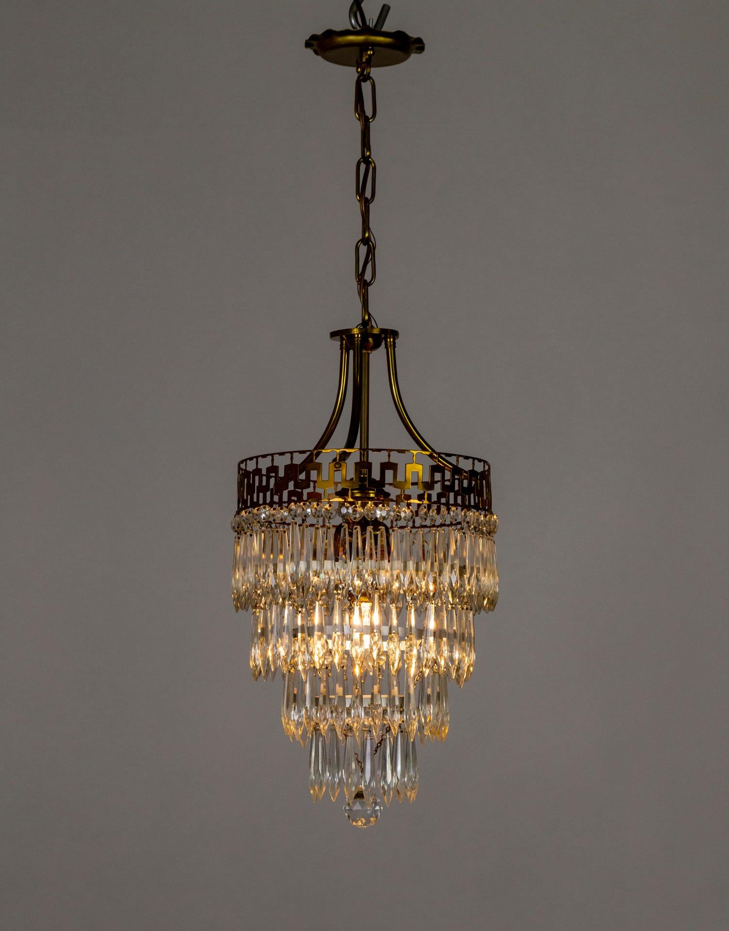 Here is a handmade, Neoclassical, 4-tiered, wedding cake-style hanging light fixture from the mid-20th century. It has the original canopy, with a chain leading to the brass stems holding the cluster of 3 medium base sockets and the brass rim cut