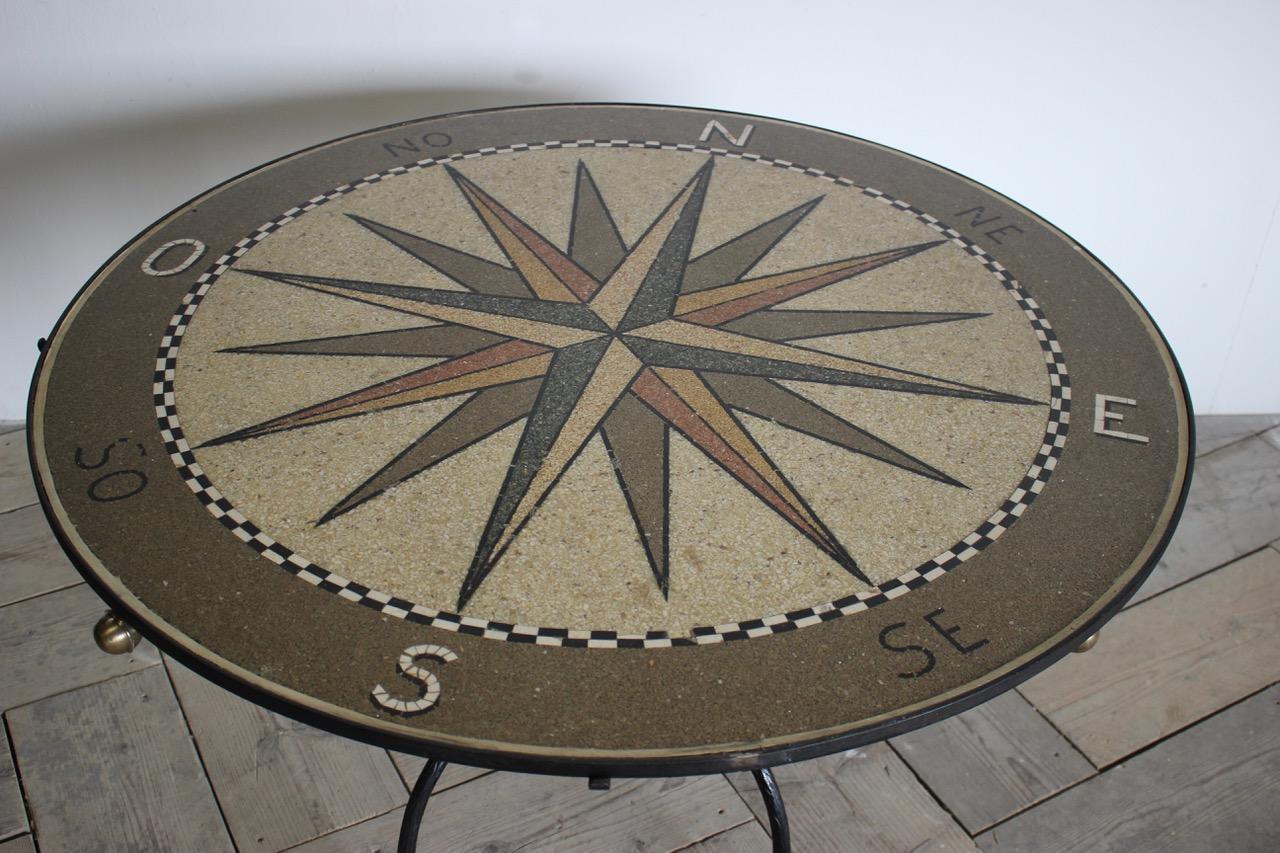A mid-20th century Spanish wrought iron table with bronze details and a mosaic style topic the form of a compass.