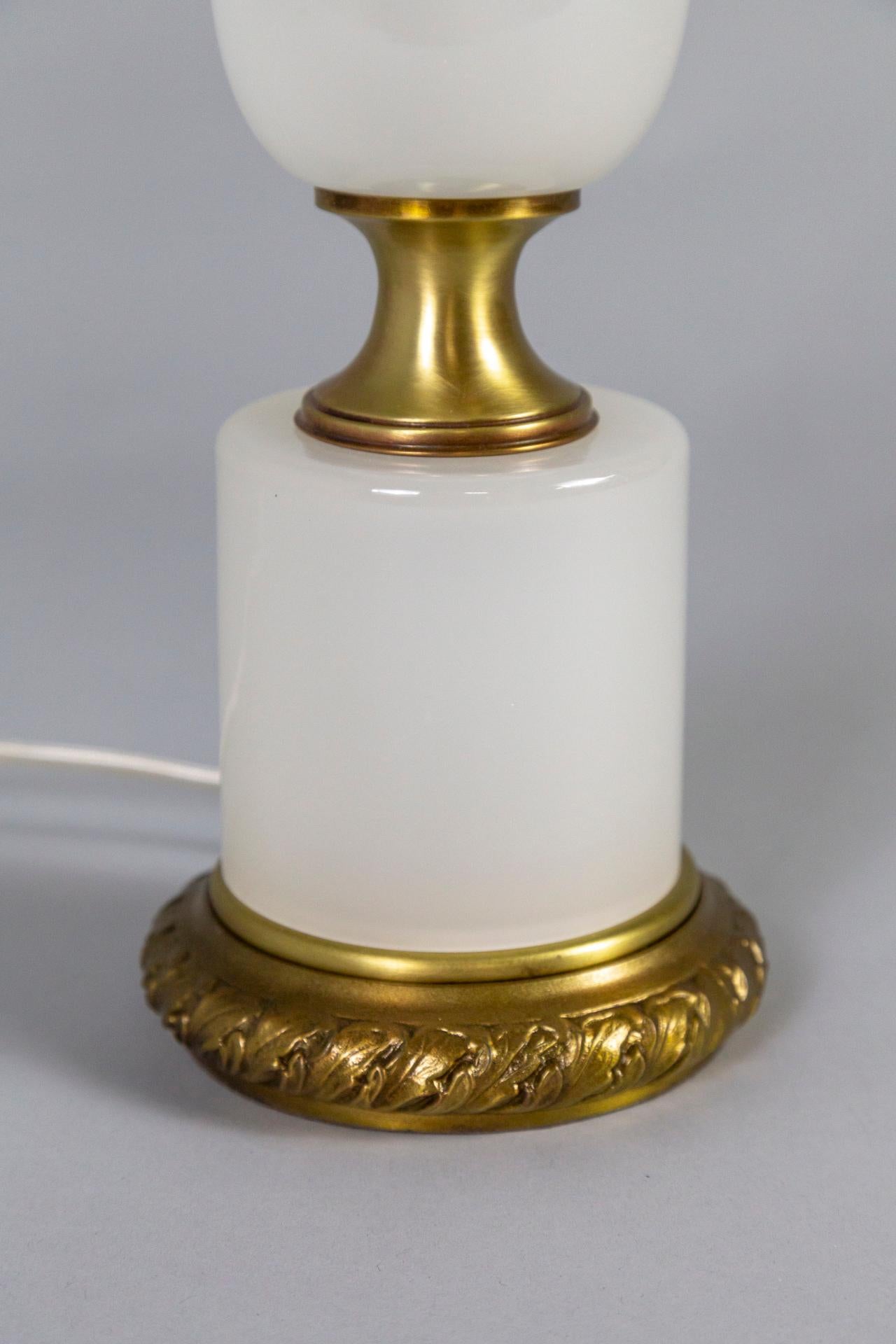 A table lamp with opaline glass that has a complex, almost smoke-like appearance. It has an elegant shape with brass accents- a base with cast acanthus leaf details. Made by Frederick Cooper design in the 1950s. Newly wired with a dimmer on the