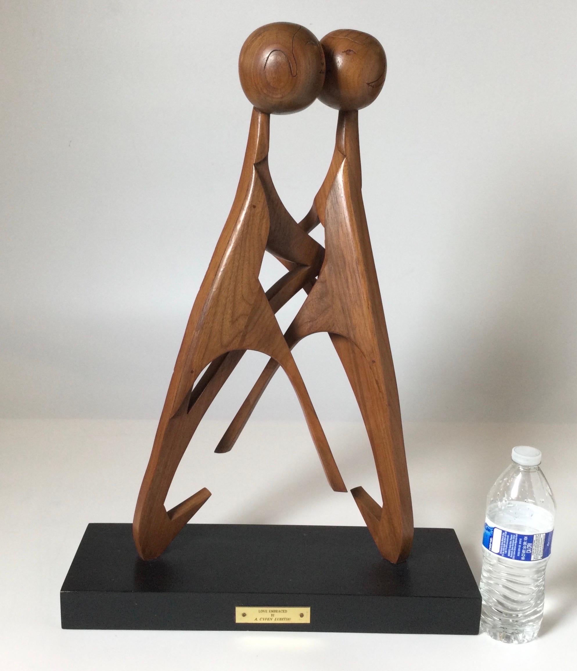 Teakholz-Skulptur „Love Embraced“ von A. Cypen Lubitsh auf ebonisiertem Holzsockel. Die 2 abstrakten Figuren, die sich umarmen, sind mit Schrauben am schwarzen Holzsockel befestigt, was die Bewegung der Figurenköpfen leicht beschleunigt. 

Cypen