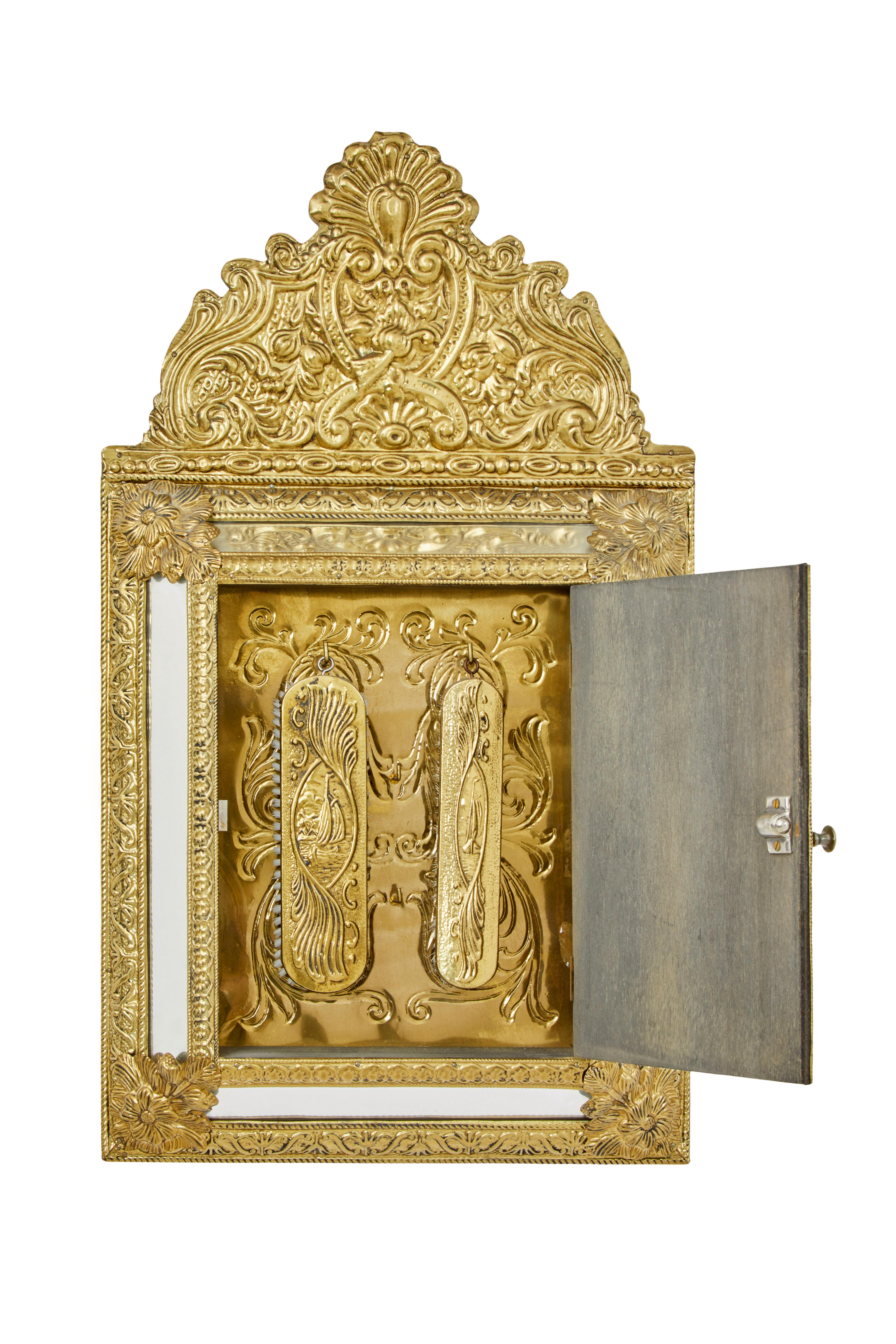Miroir à coussin de bonne qualité dans le goût du mouvement esthétique, vers 1950.

Surface décorative en laiton pressé avec fleurs et moulures. Miroir à coussin surélevé avec une seule porte à l'avant, qui s'ouvre sur un autre intérieur en laiton