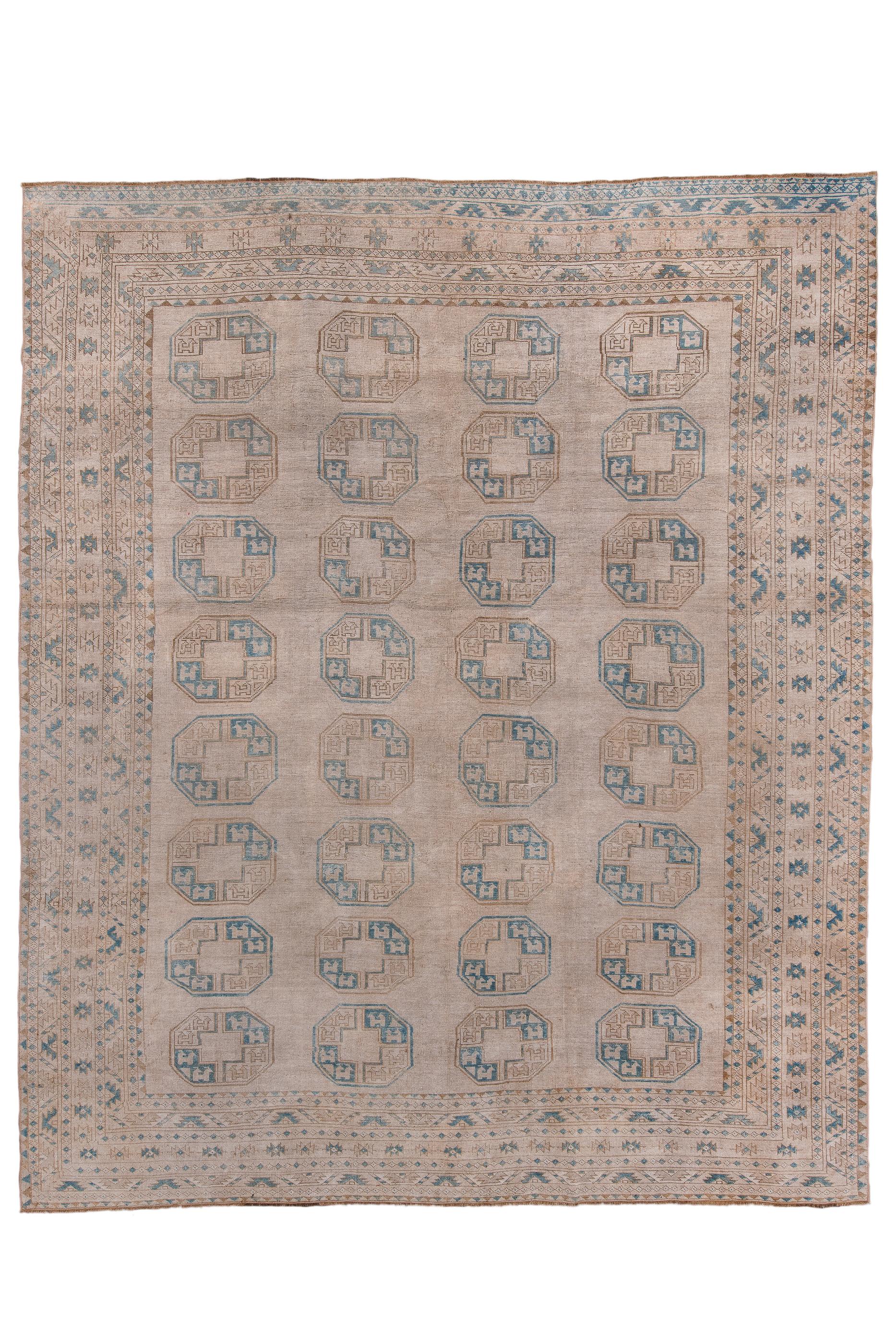 This nearly square nomadic piece from northern Afghanistan show a light tan field with four columns, each of  eight octagonal tauk noska (chicken) guls, all well-spaced, within a border system  including two stripes with half-ashiks and a central 