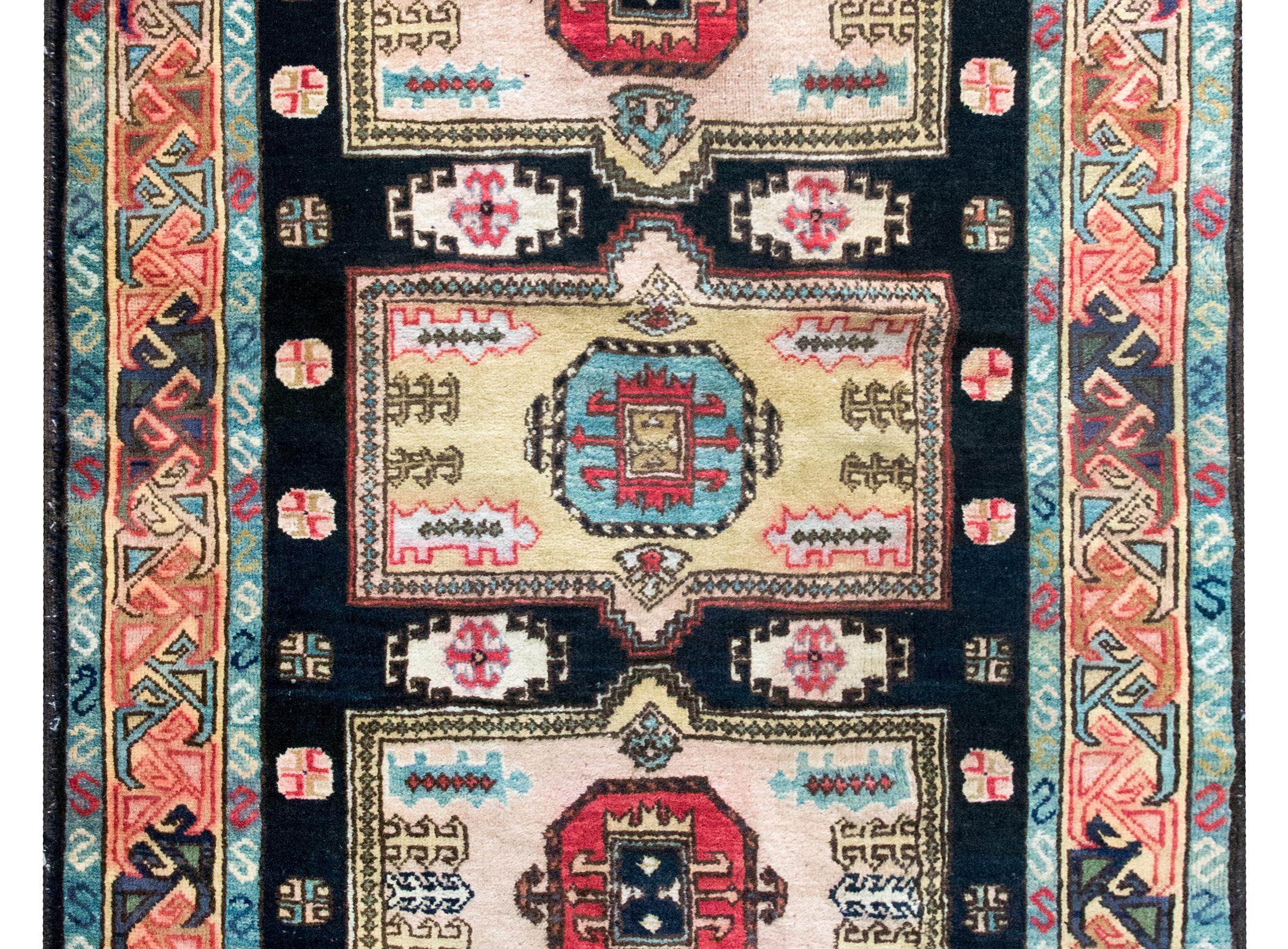 Un meraviglioso tappeto Kazak afghano della metà del XX secolo con tre grandi medaglioni centrali, ognuno dei quali è tessuto con motivi floreali stilizzati e vive in un campo di altri fiori stilizzati, il tutto circondato da un bordo di viti