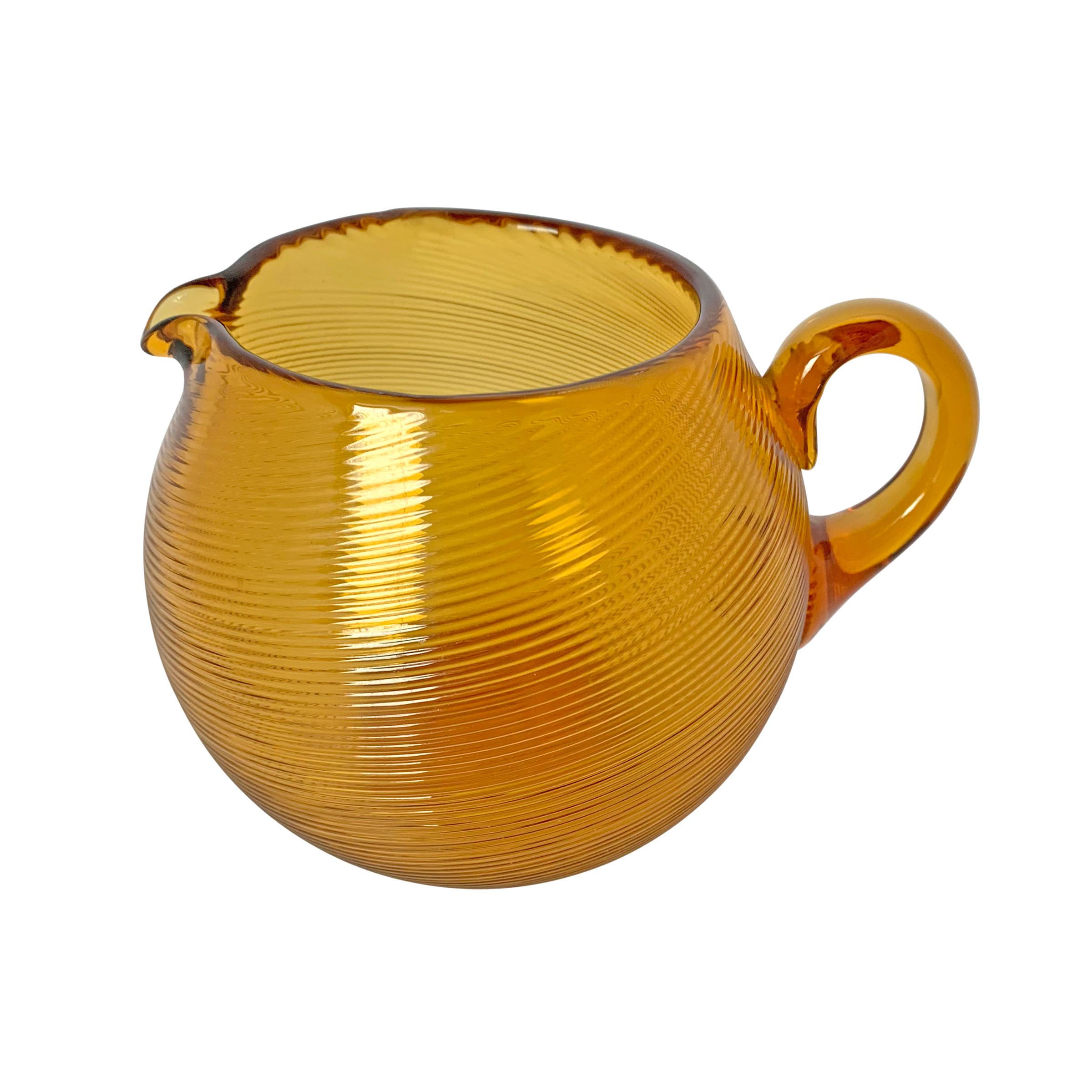 A mid-20th century American hand blown amber glass pitcher with a beautiful bold round form and a tightly swirled pattern.