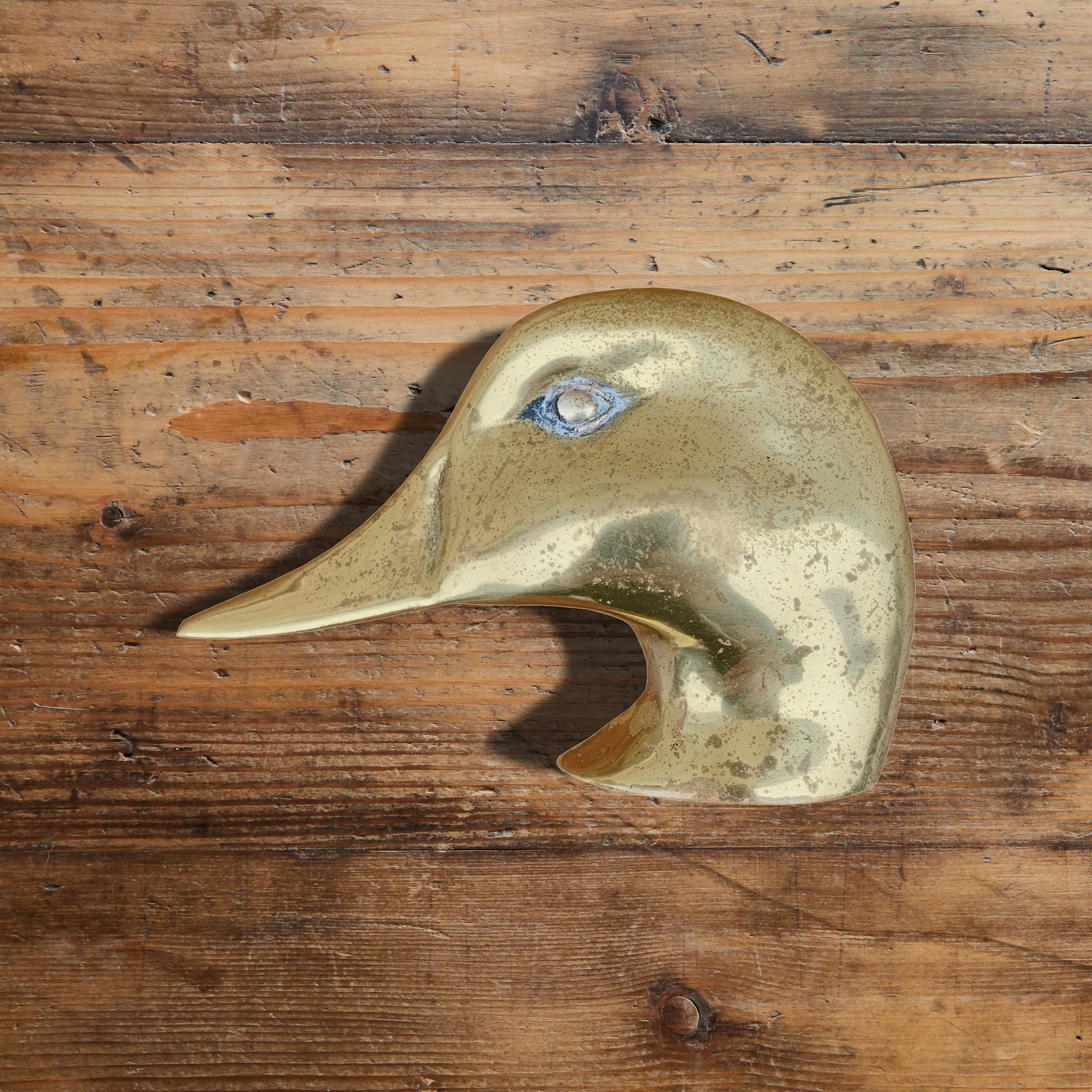 A whimsical mid-20th century American cast brass duck head door knocker.