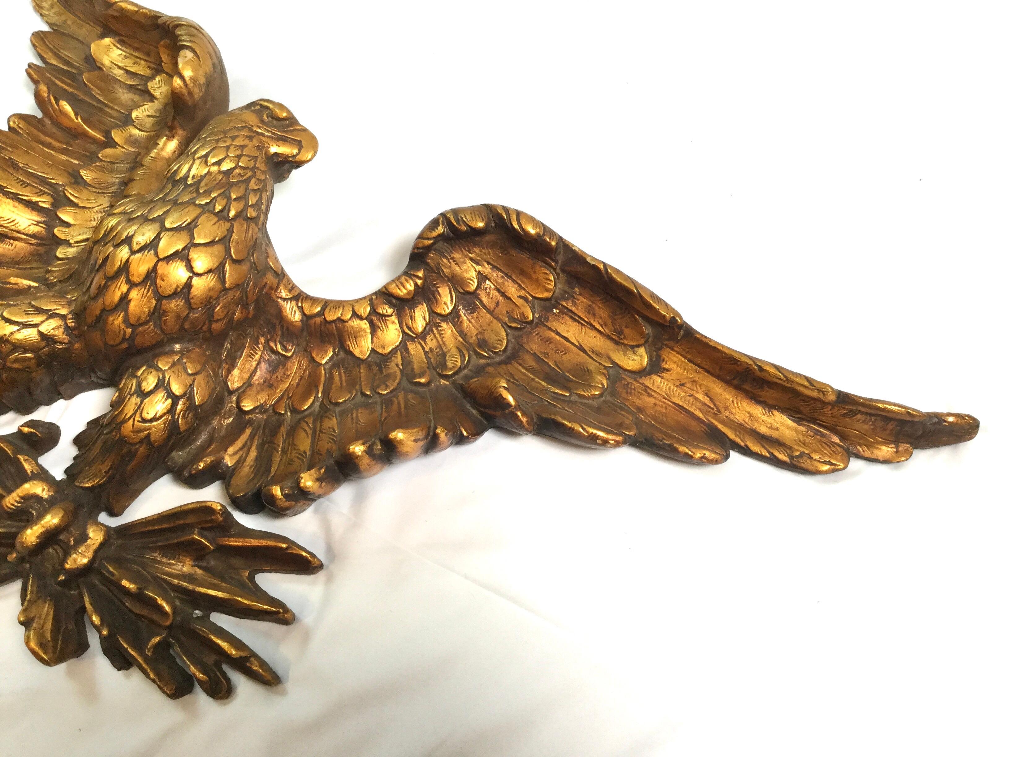 An aged gold American eagle wall sculpture circa 1950s. The eagle with spread wings in a partitive pose. High relief detail.