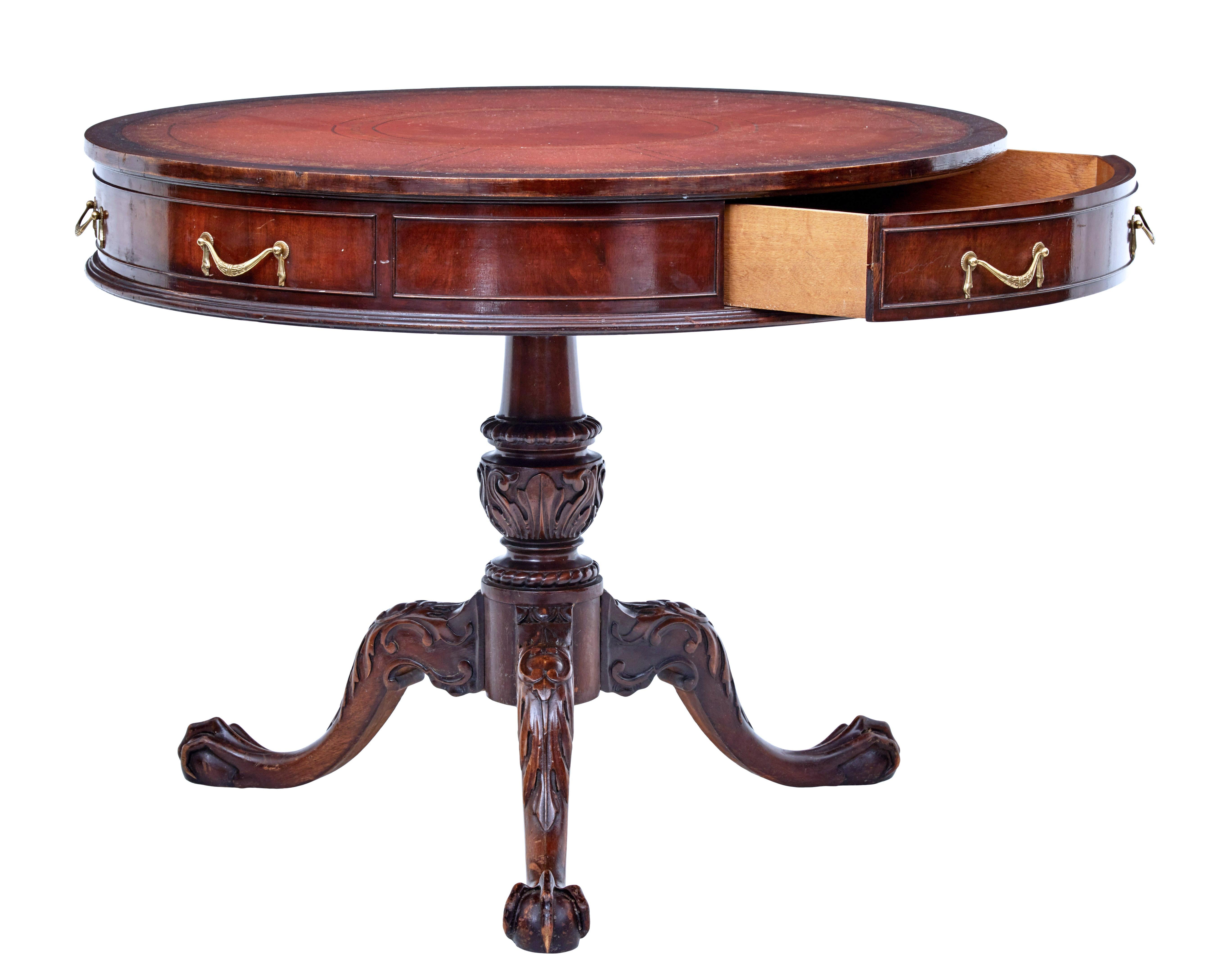 1960s mahogany drum table by imperial grand rapids Michigan.

Circular red leather top decorated with gold and black tooling. 1 single drawer and a further 2 dummy drawers. Standing on a heavily carved tripod base, terminating on large ball and