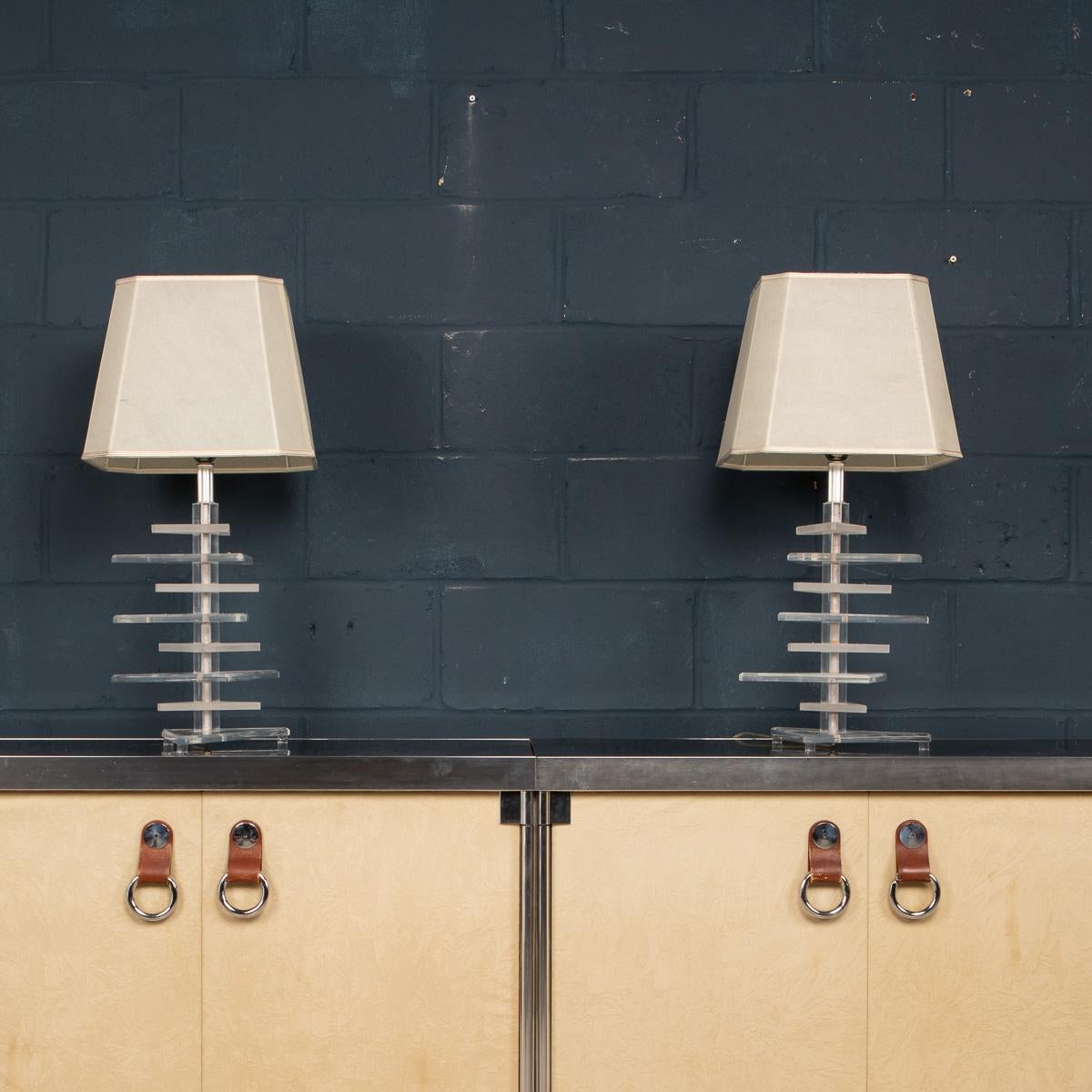 A chic pair of Mid-Century Modernist stacked Lucite lamps, realised in the manner of Karl Springer. A thick base supports interchanging sections of solid faceted, rectangular Lucite, some frosted, some clear. These Art Deco inspired lamps offer a
