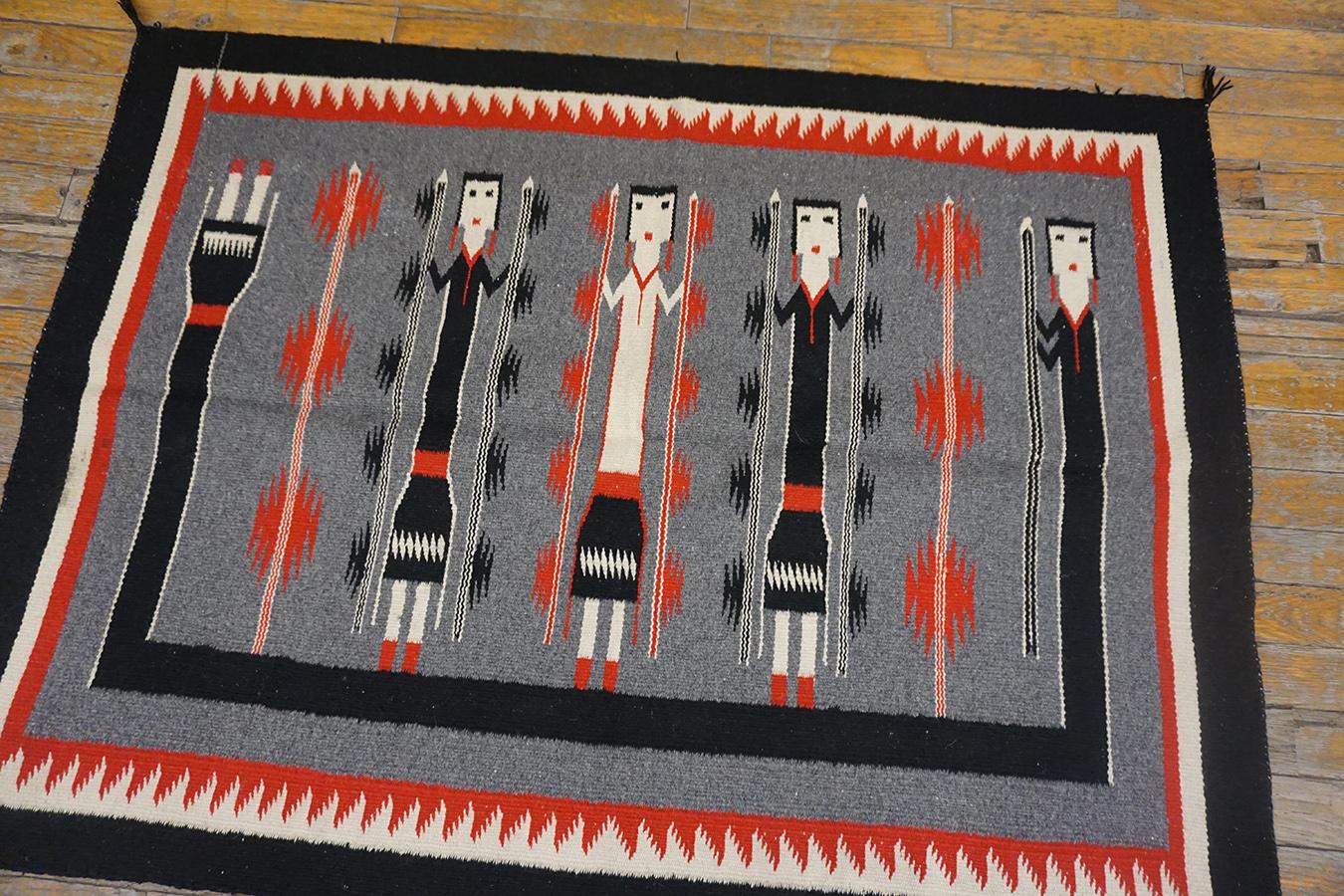 The black border of this figural Yei rug frames the grey field with three standing dancers and a fourth stretched and bent around three sides. 
Yei rugs are copies after intentionally transient sand paintings and are 20th century innovation. This