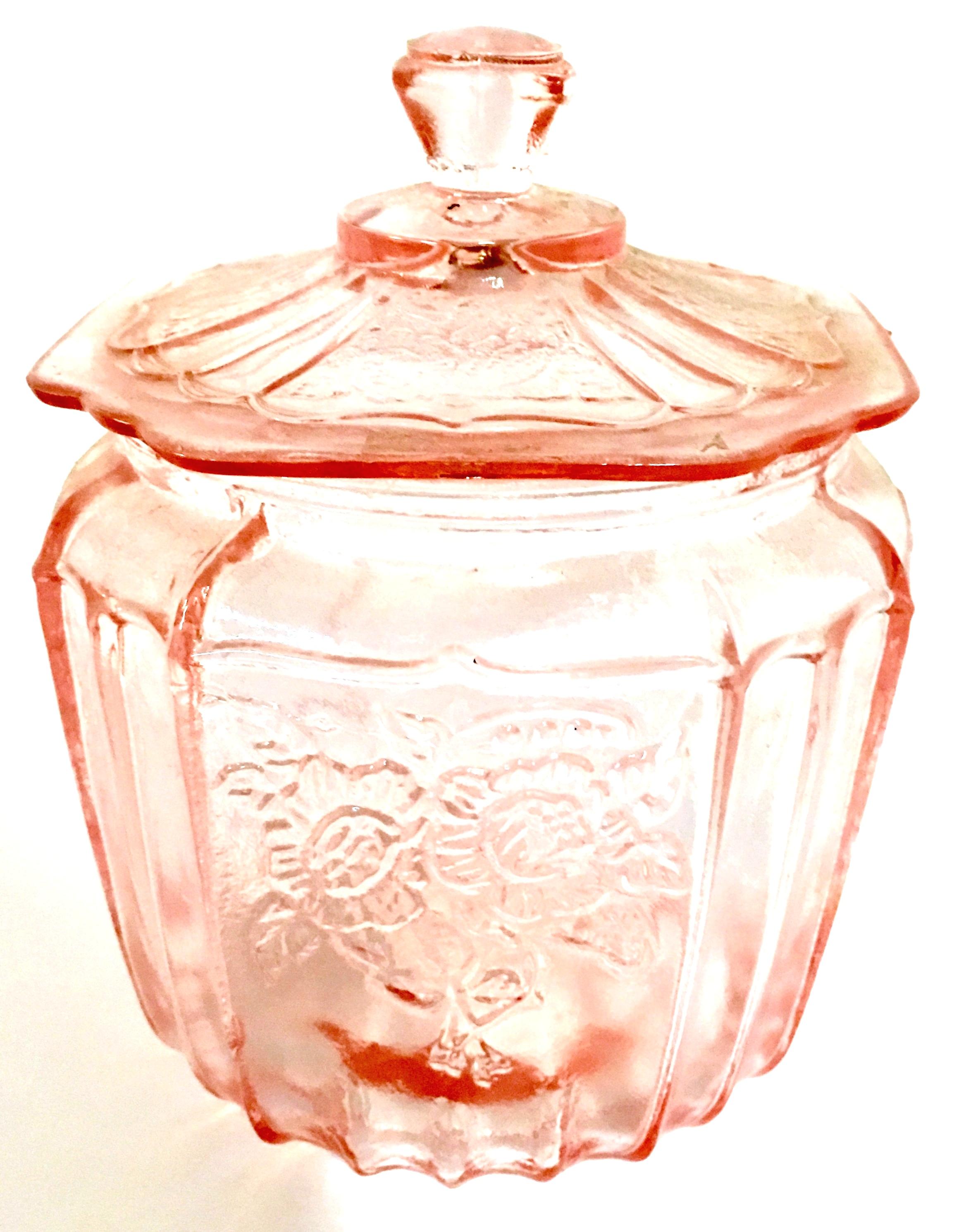 Mid-20th century American pink depression glass lidded cookie jar. Features a raised rose floral pattern.