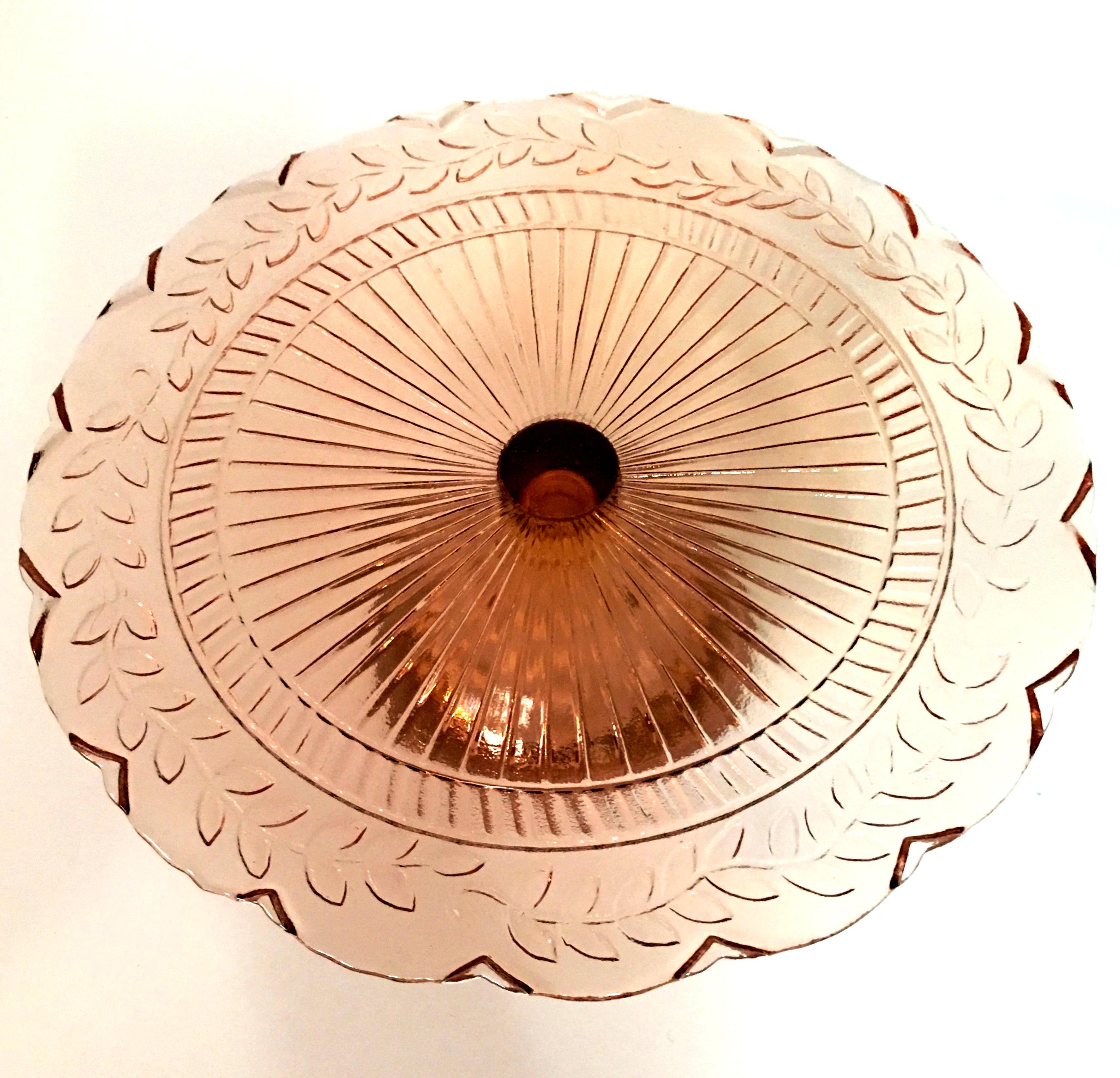 Mid-20th century American pink depression glass pedestal cake plate. Features a laurel leaf motif with scalloped edge.
