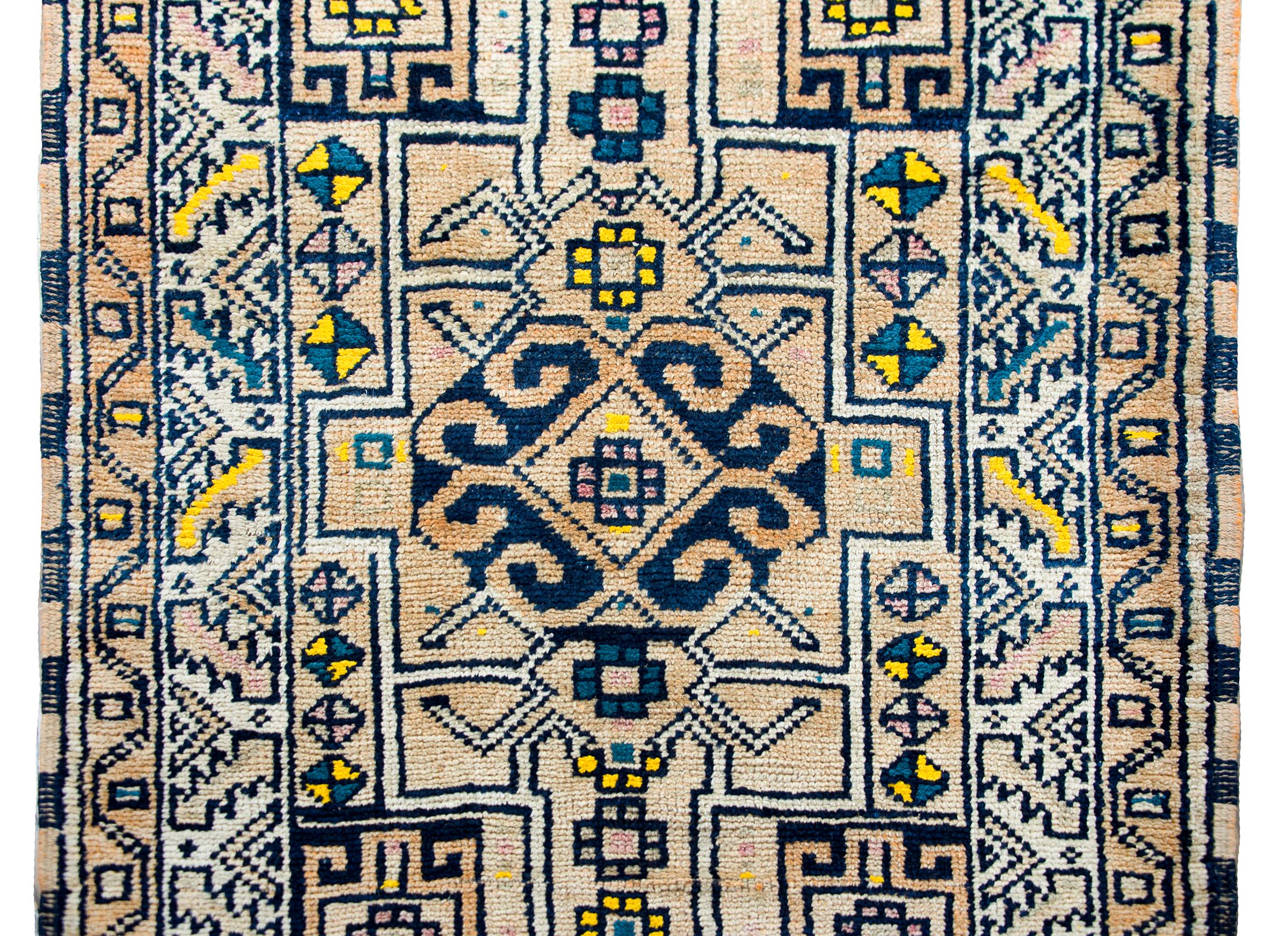 A bold mid-20th century Anatolian Turkish Runner with a repeated geometric lattice pattern with stylized floral medallions, and surrounded by a border of more geometric patterns, and all woven in light and dark indigo, gold, cream, and white wool.