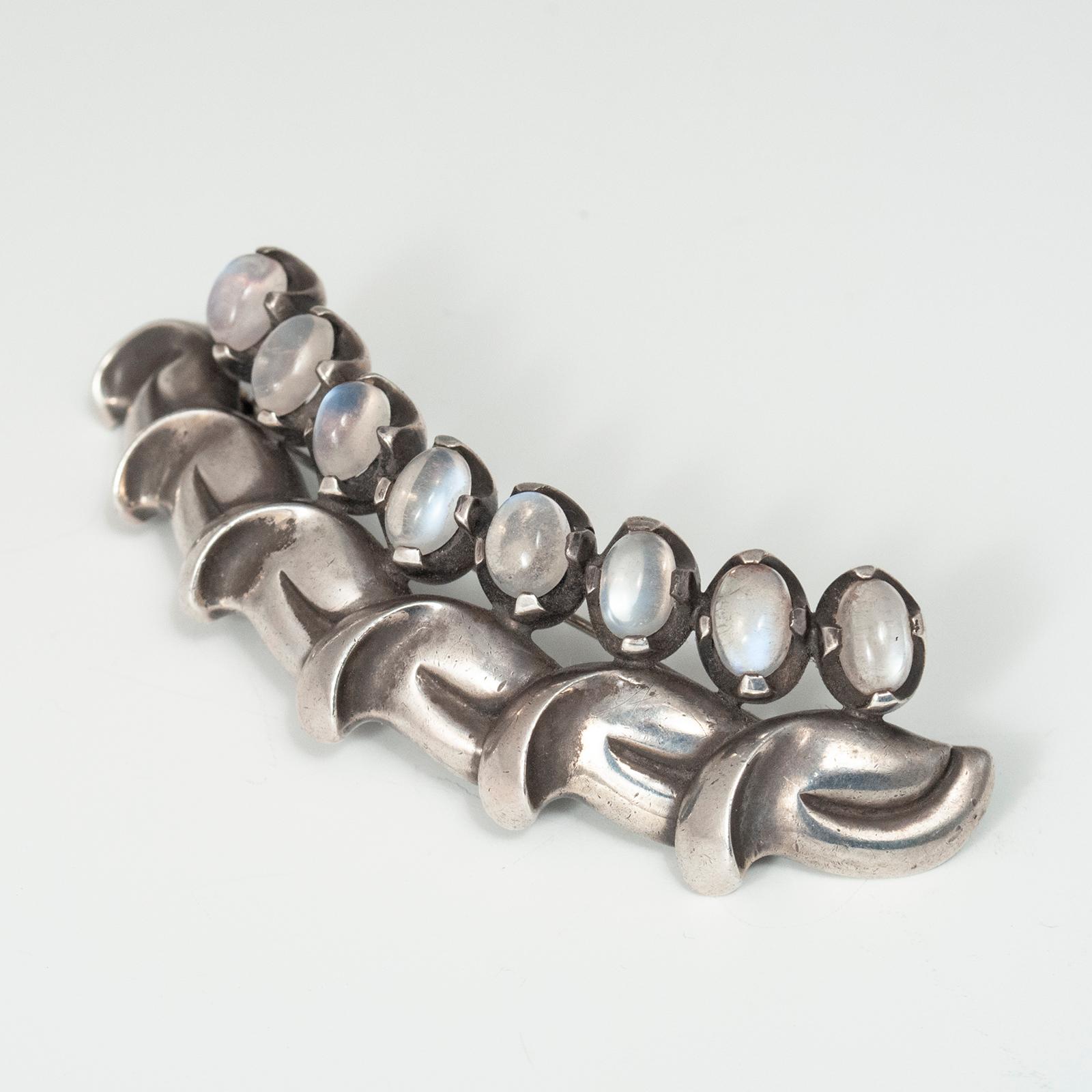 Spilla in argento e pietra di luna di Antoñio Pineda (1919-2009) della metà del XX secolo, Taxco Mexico

Questa splendida spilla in argento contiene otto cabochon di pietra di luna dal taglio ovale incastonati in una fila curva sopra sei foglie