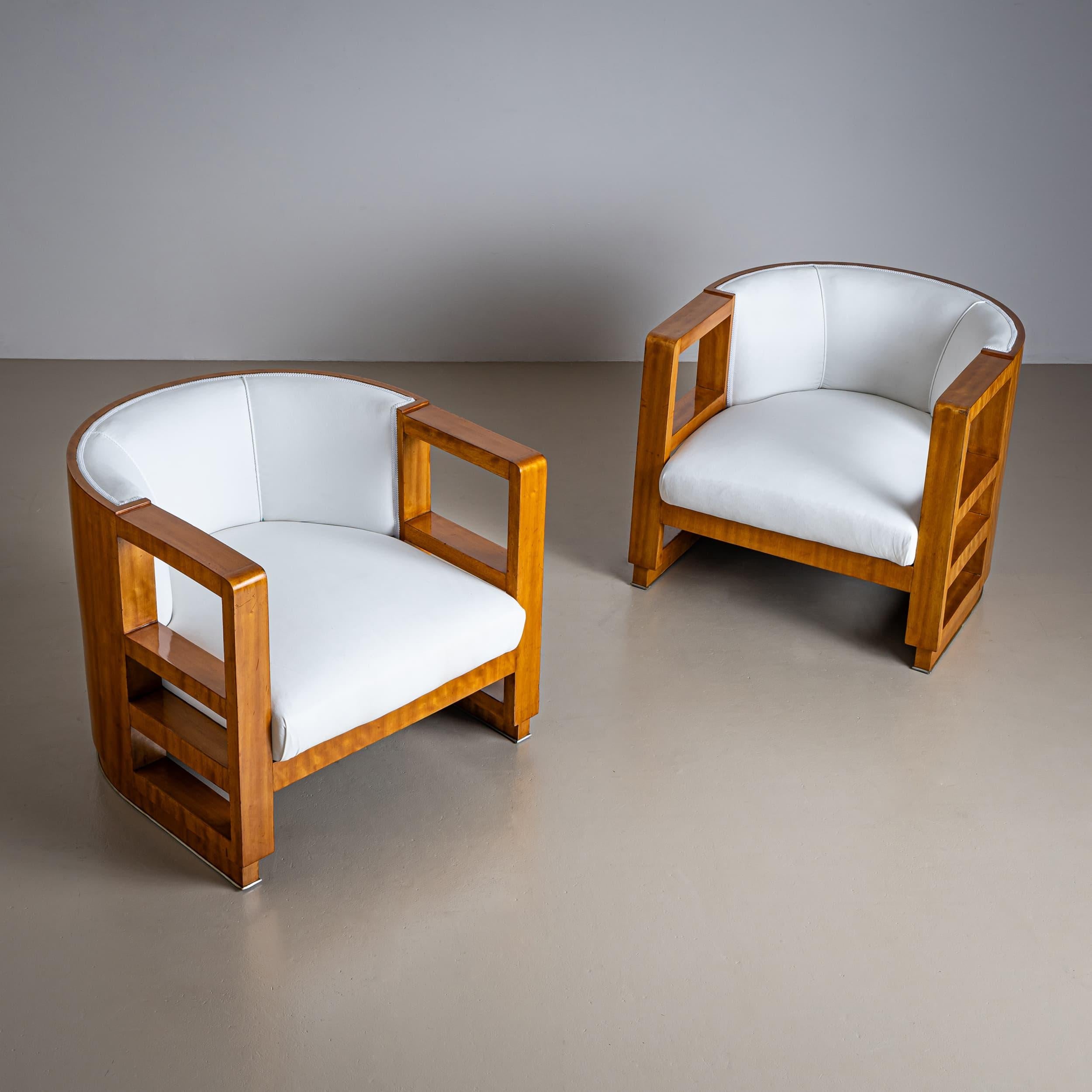 Paire d'élégants fauteuils Art Déco, avec des cadres doucement arrondis et des découpes rectangulaires distinctives à la hauteur de l'accoudoir. Nouvellement retapissées et recouvertes d'un tissu blanc de haute qualité, ces chaises mettent en valeur