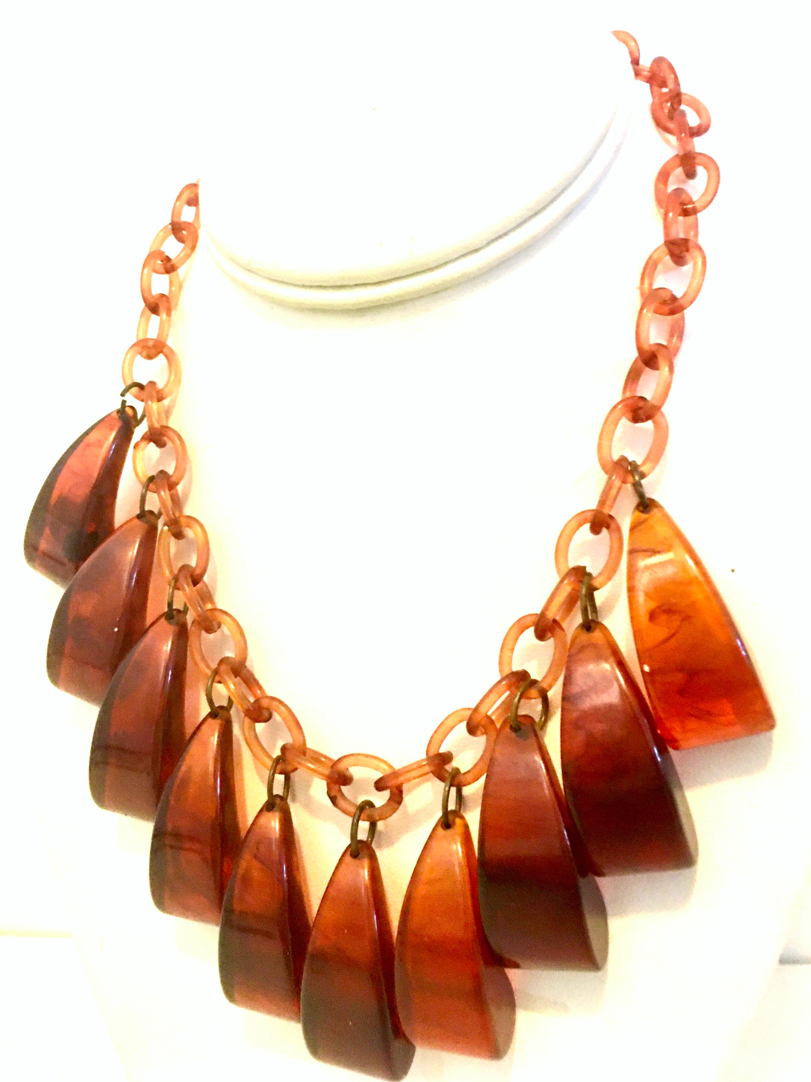 Mid-20th Century Art Deco Root Beer Bakelite & Celluloid Chain Link Necklace. This coveted and rare choker style necklace features Celluloid chain link detail with 10 large organic form hanging charm ornaments. The locking claps is brass. Each of
