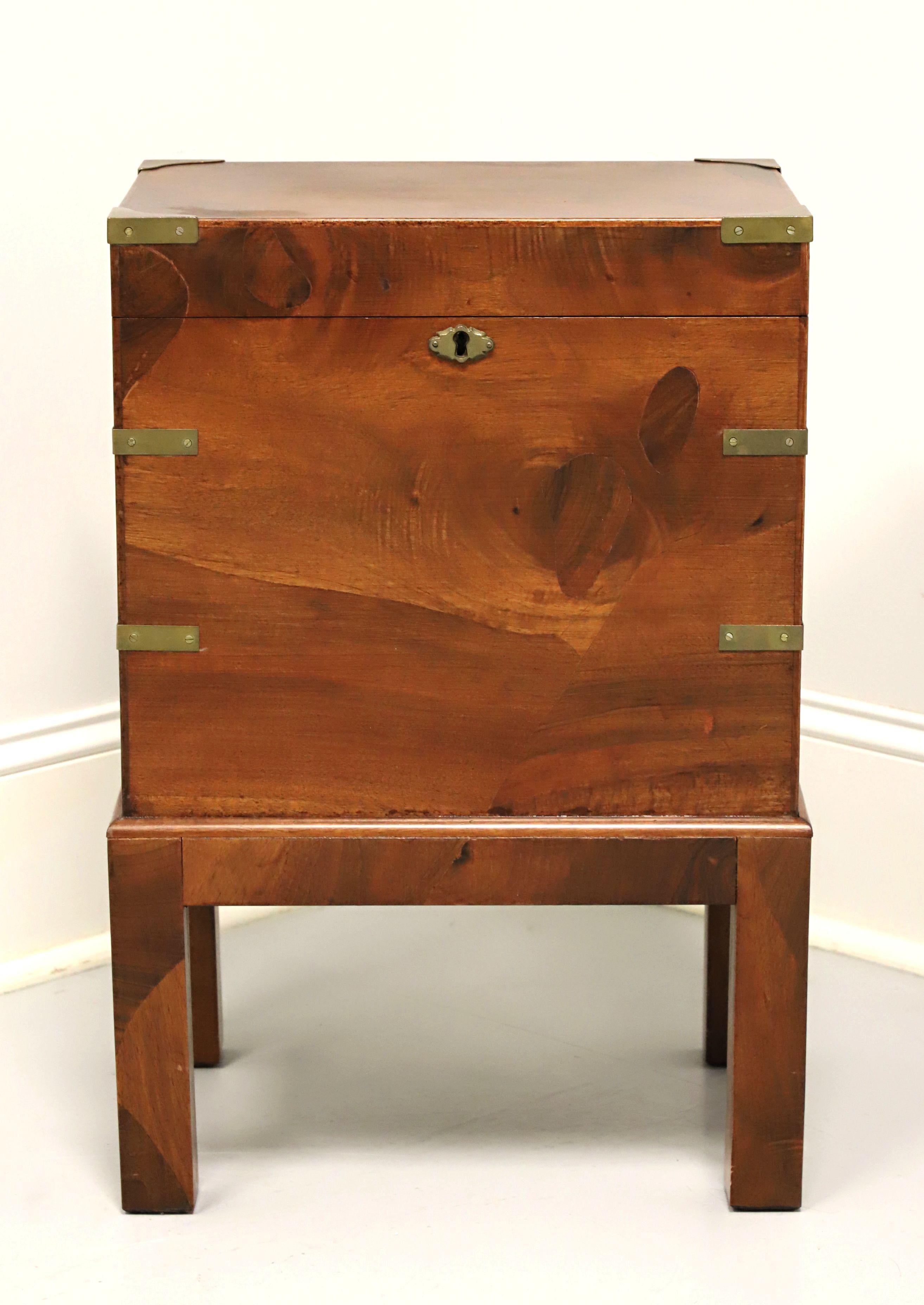 An Asian influenced Campaign style decorative chest affixed to stand, unbranded. Walnut, or similar hardwood, lift up lid on a chain, decorative brass accents, and square straight legs. Features a tall interior suitable for wine bottle or other