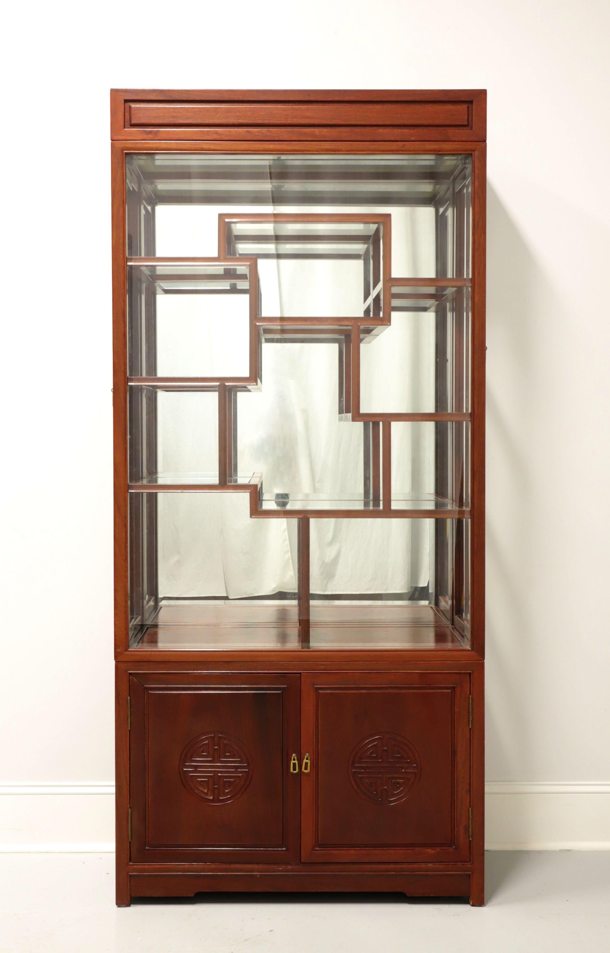 An Asian Chinoiserie style curio display cabinet, unbranded. Solid rosewood with Chinoiserie carvings and brass hardware. Upper cabinet features an opaque glass top to allow light, a solid glass front, distinctive fretwork design with eight fixed