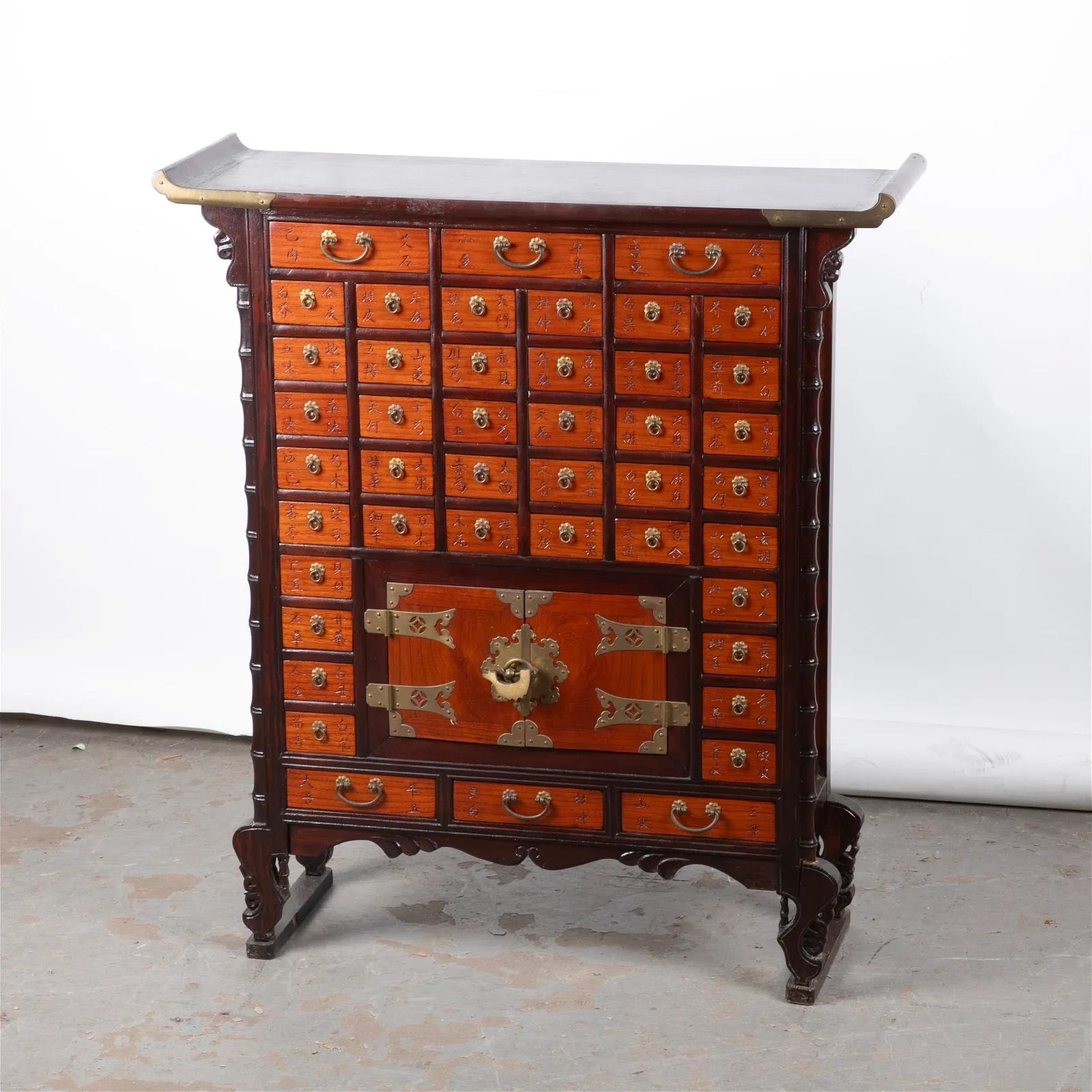 Consola botica de estilo asiático, parte superior de borde curvo acentuado en latón y columnas laterales de bambú de imitación.


