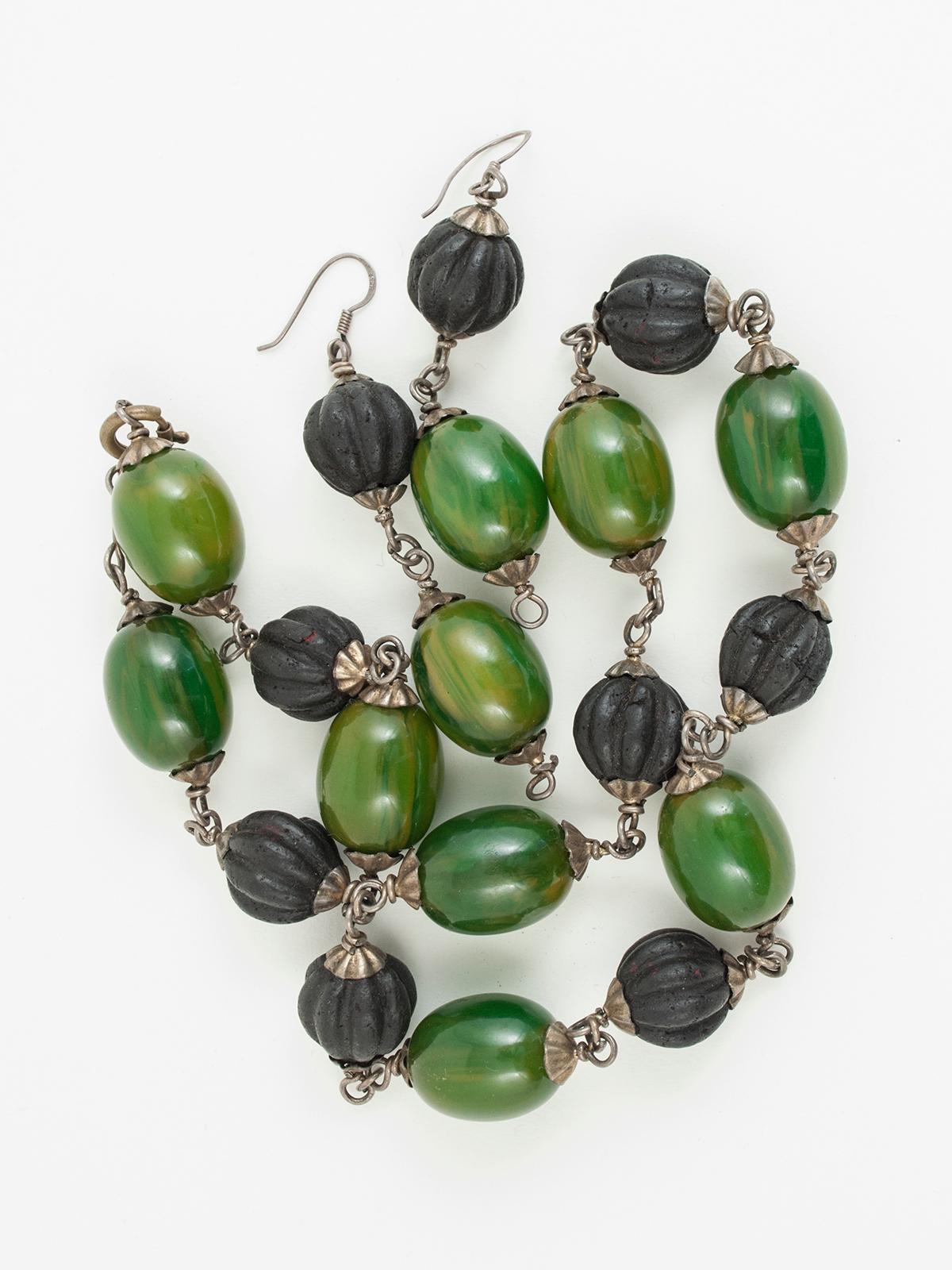 Mid-20th century Bakelite and amber paste bead necklace and earrings, Tunisia

A vintage necklace and earring set made of green/yellow bakelite beads, which are known as 'faturan', and melon-shaped beads created from amber paste; there is a very